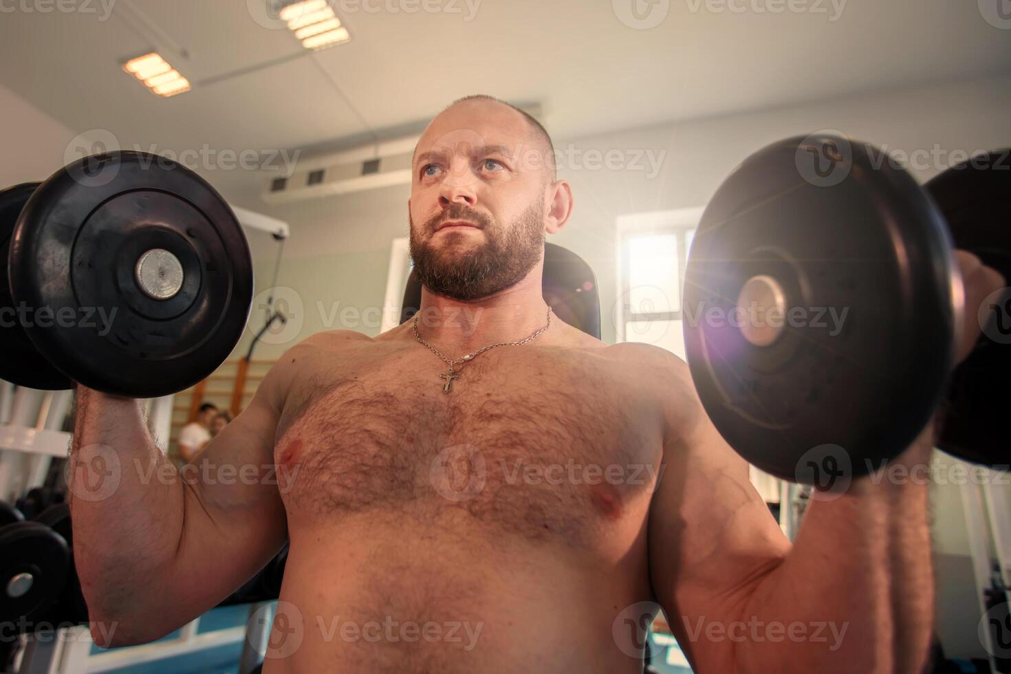 Bearded man lifting weights in the gym. Sportsman athlete bodybuilder in the gym. photo