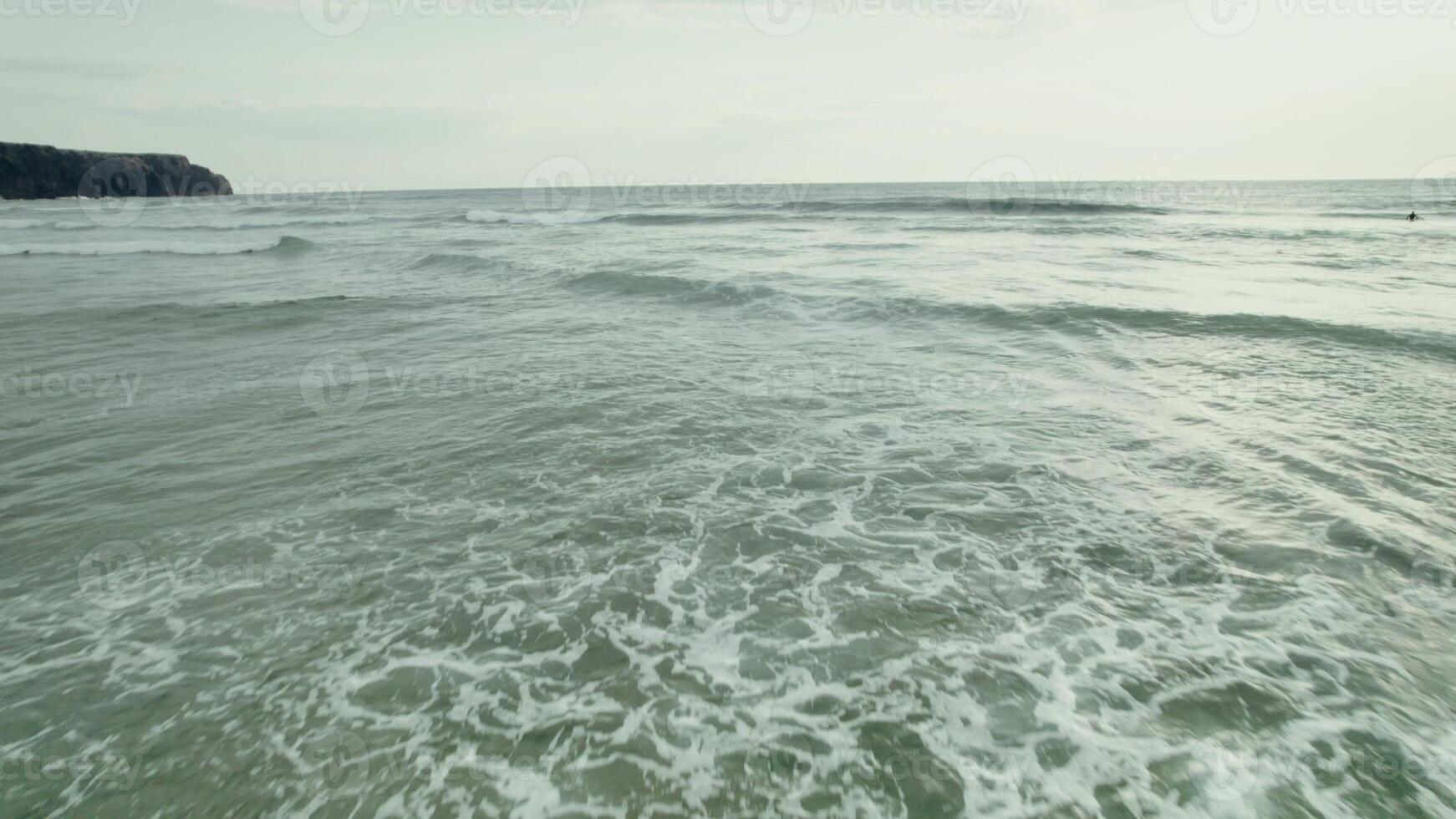 The sea with large waves. Rocks on the shore in the distance photo