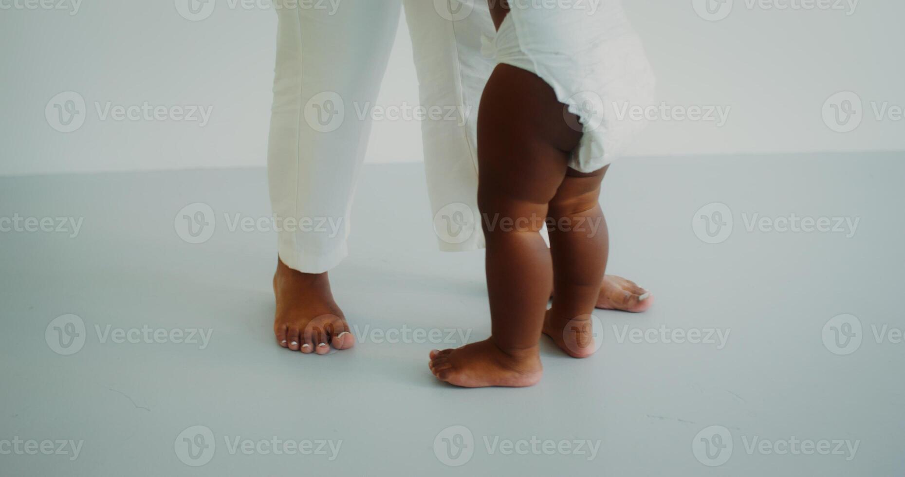 Naked chubby baby legs next to mom's legs photo