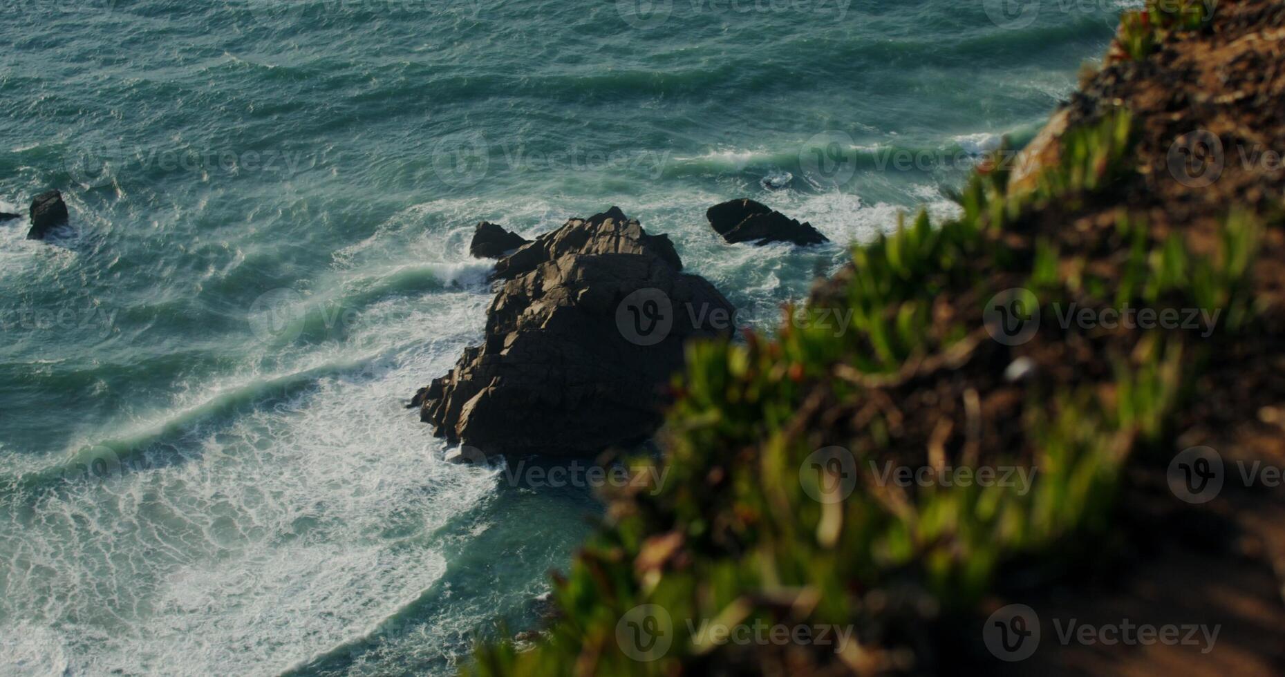 Top view of rocky seashore, a boulder peeks out of the water photo