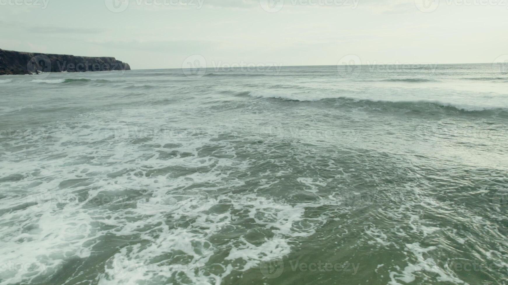 The drone flies low and fast over the sea with large waves. Rocks on the shore photo