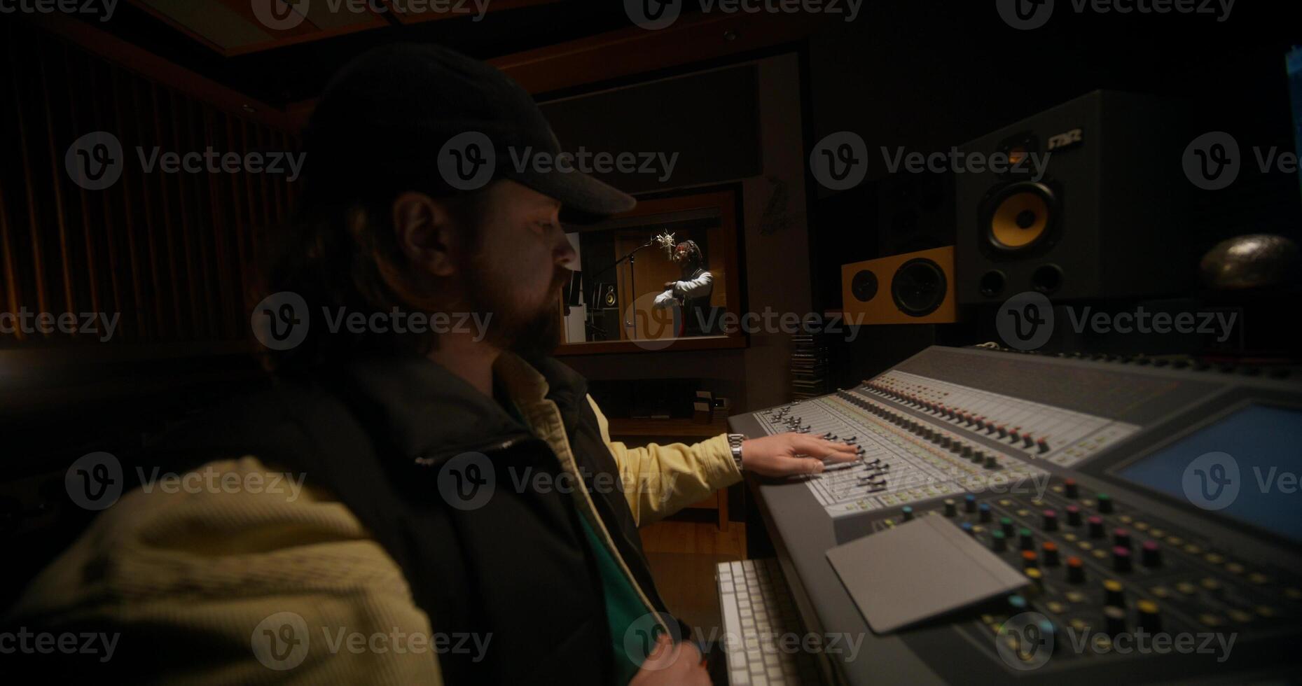 Working in a recording studio. A music engineer controls an audio mixer when rapper records a song photo