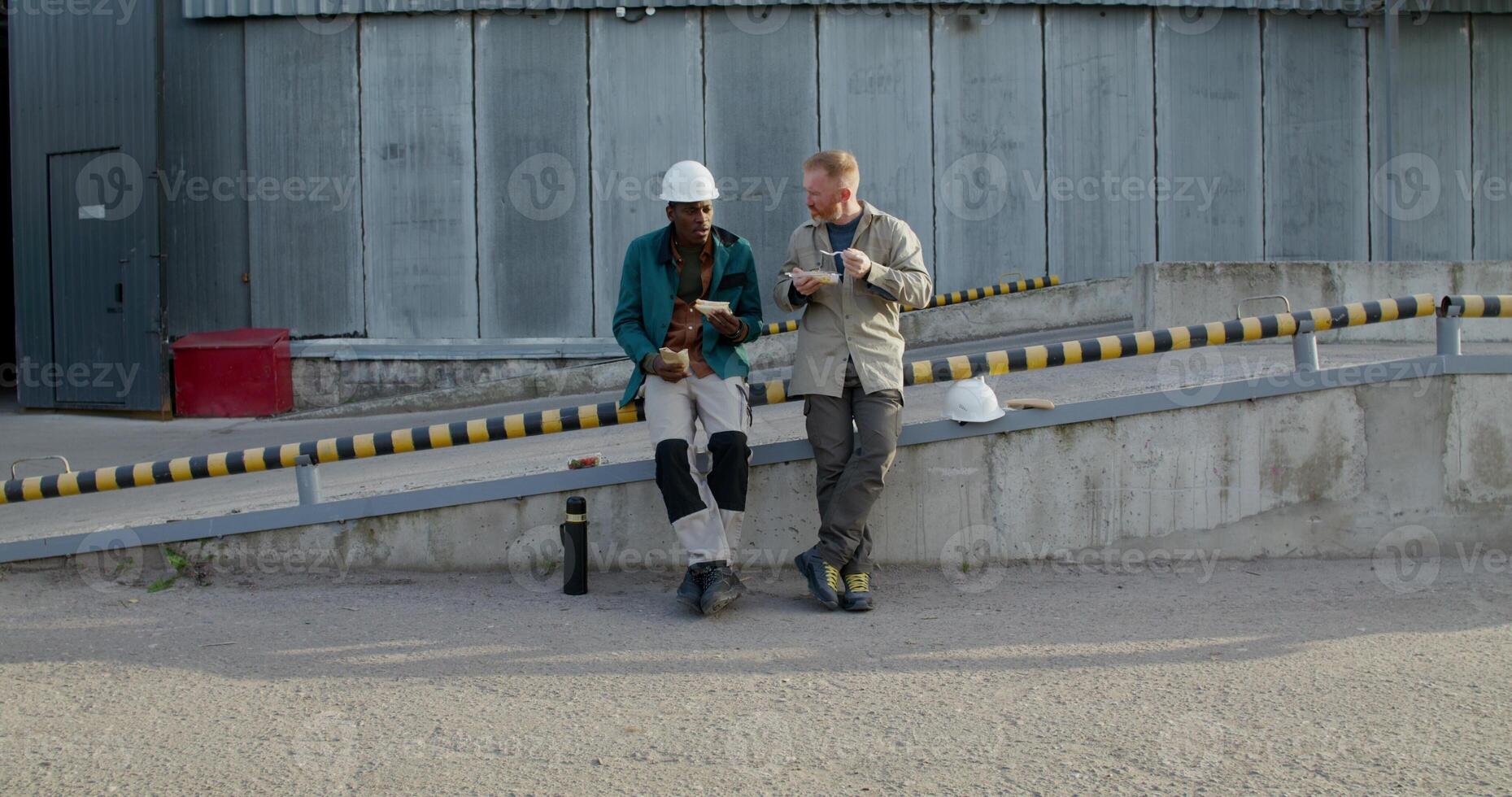 Two workers in uniform are having lunch sitting outside near the factory. photo