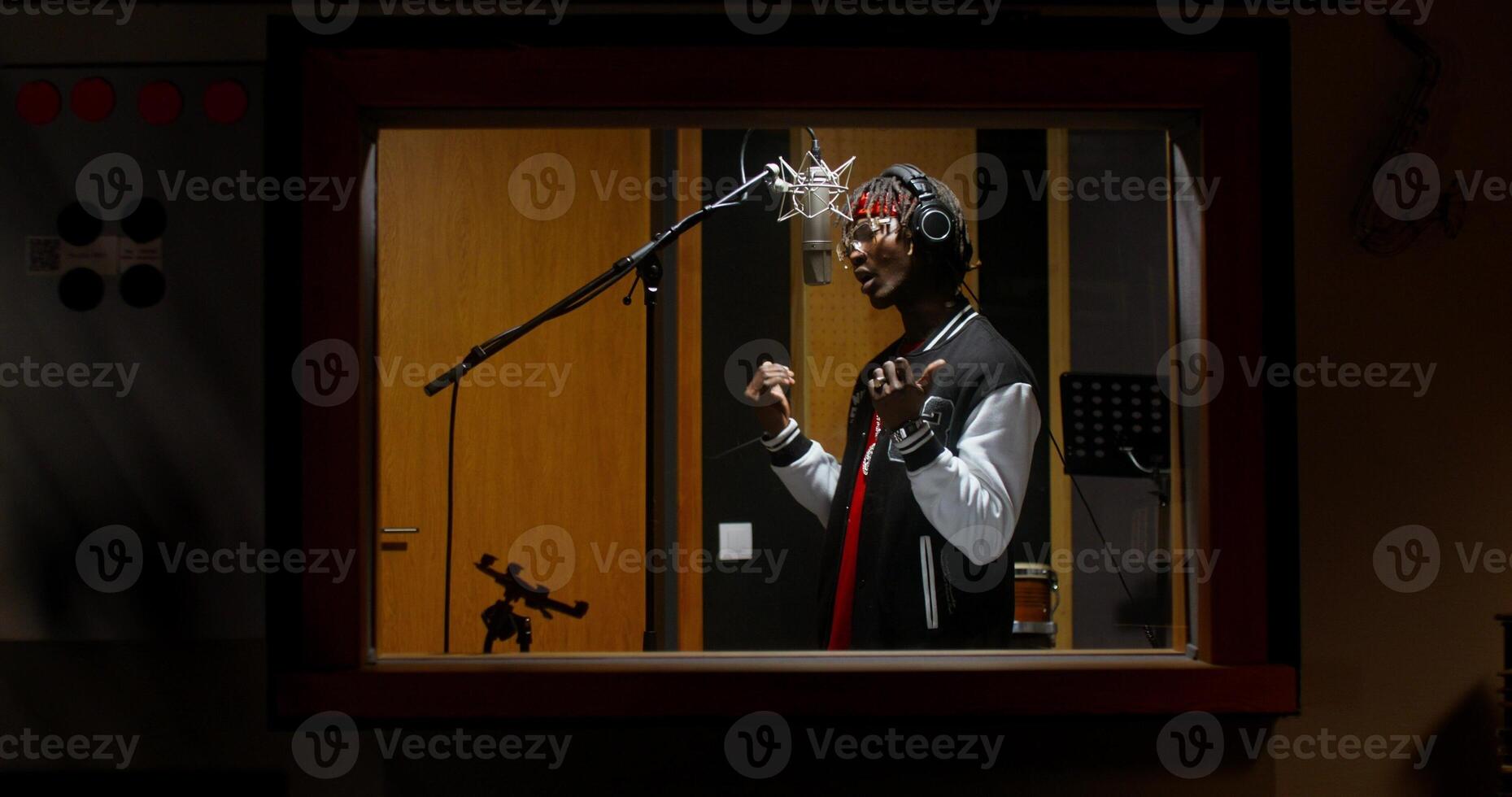 The rapper is recording a song in a recording studio. View through the window photo