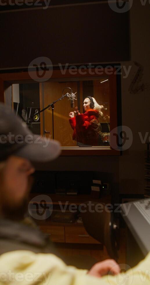 Working in a recording studio. The sound engineer uses an audio mixer. The singer sings into the microphone photo