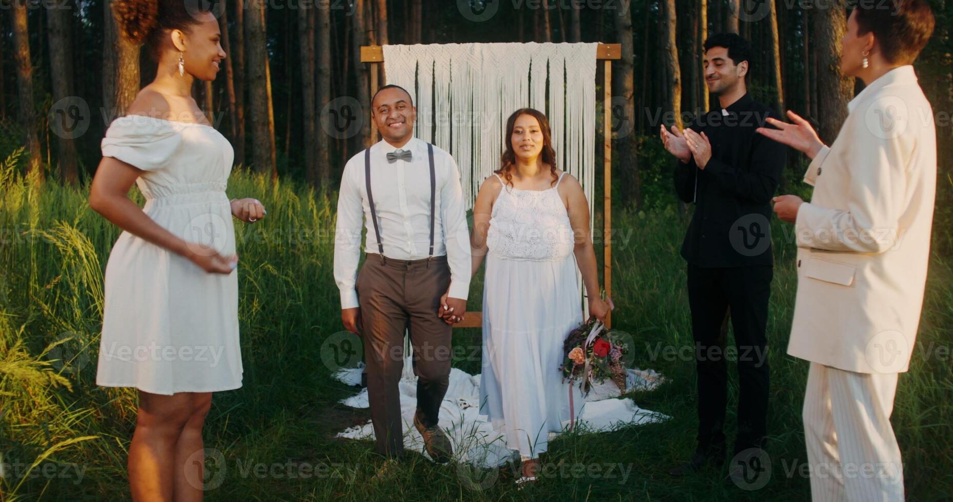 The bride and groom hold hands passing by the guests after the wedding. Guests shower the young with rice photo