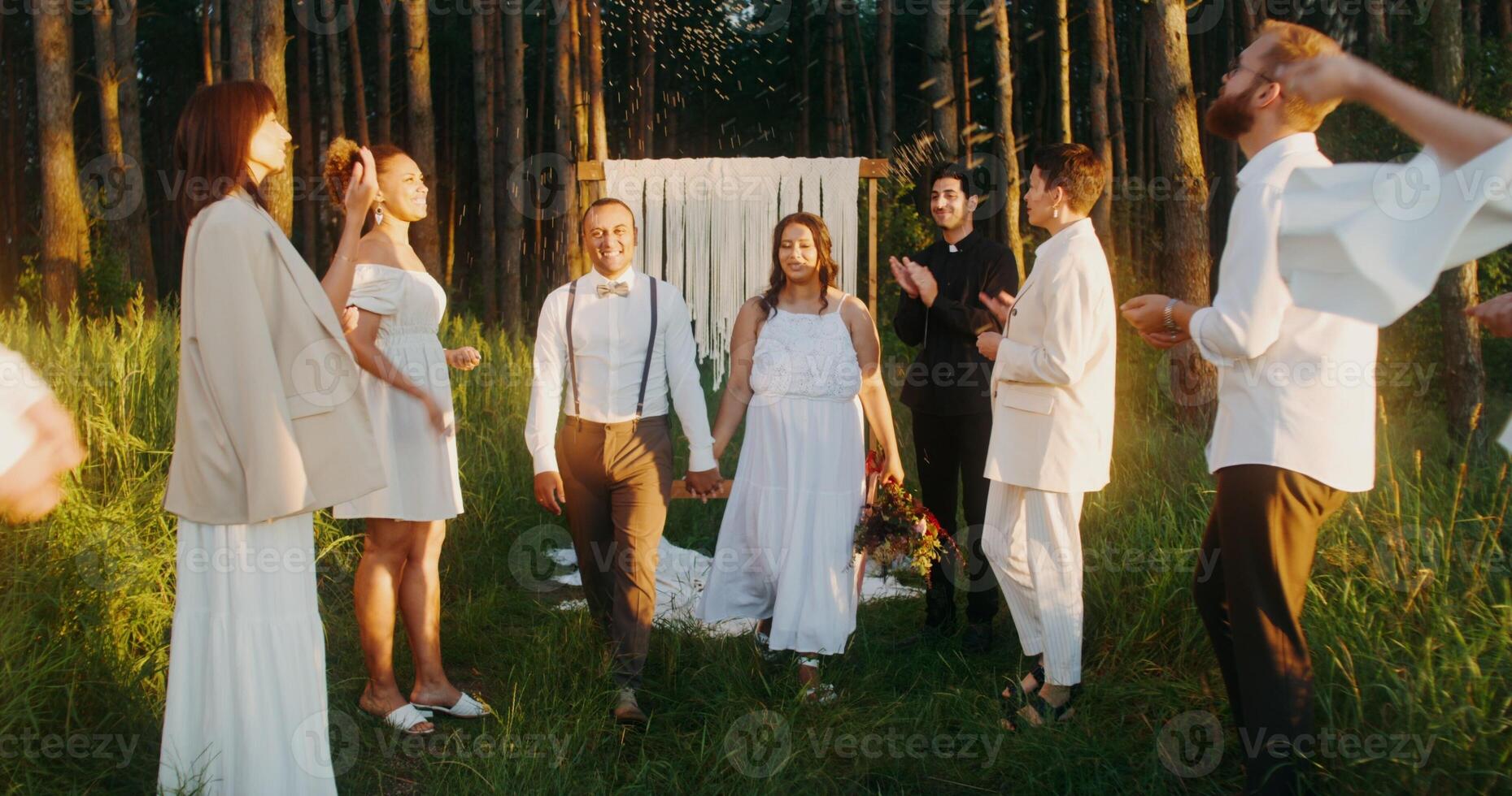 The bride and groom hold hands passing by the guests after the wedding. photo