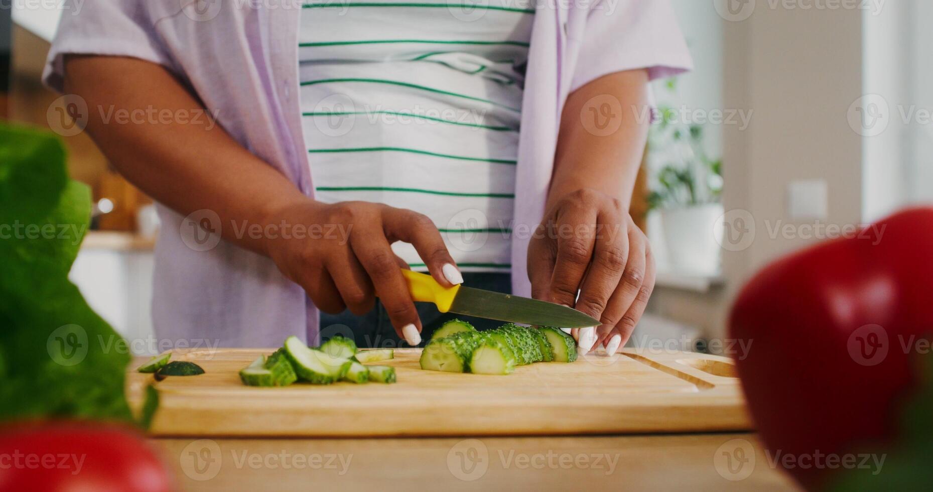 Women's hands cutting a cucumber while preparing a salad in the kitchen, there is no face photo