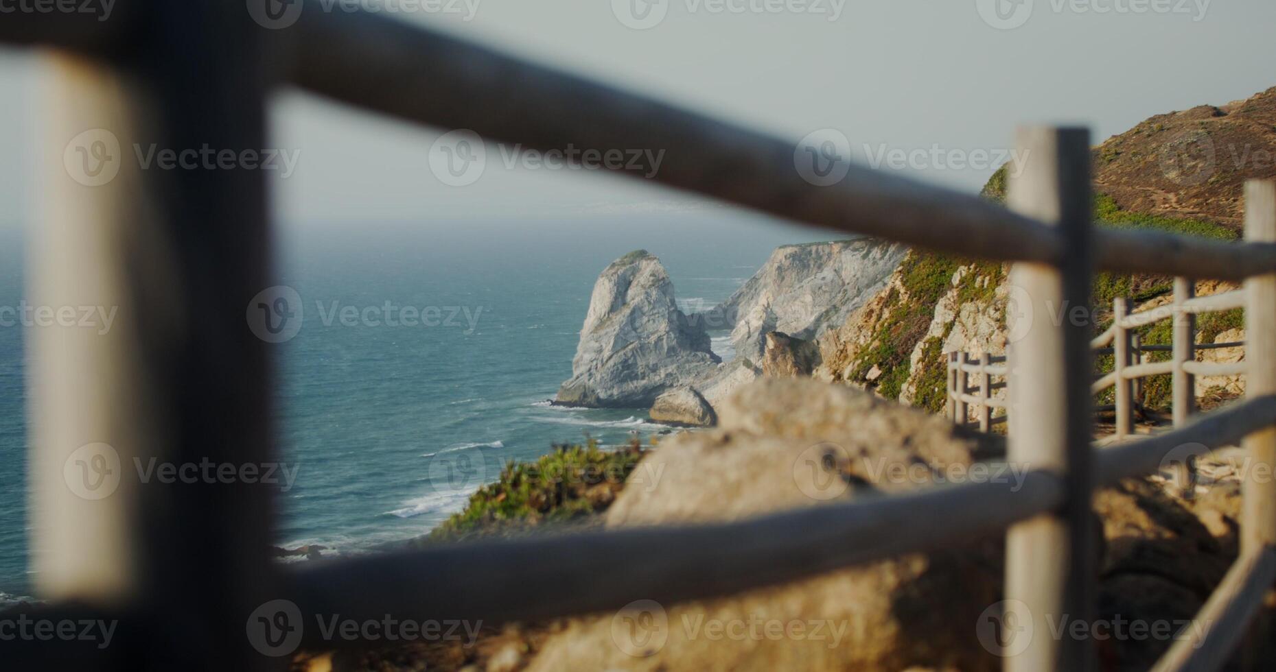 View of the sea washing the rocky shores and ledges. View from the top of the mountain from the observation deck through the fence photo