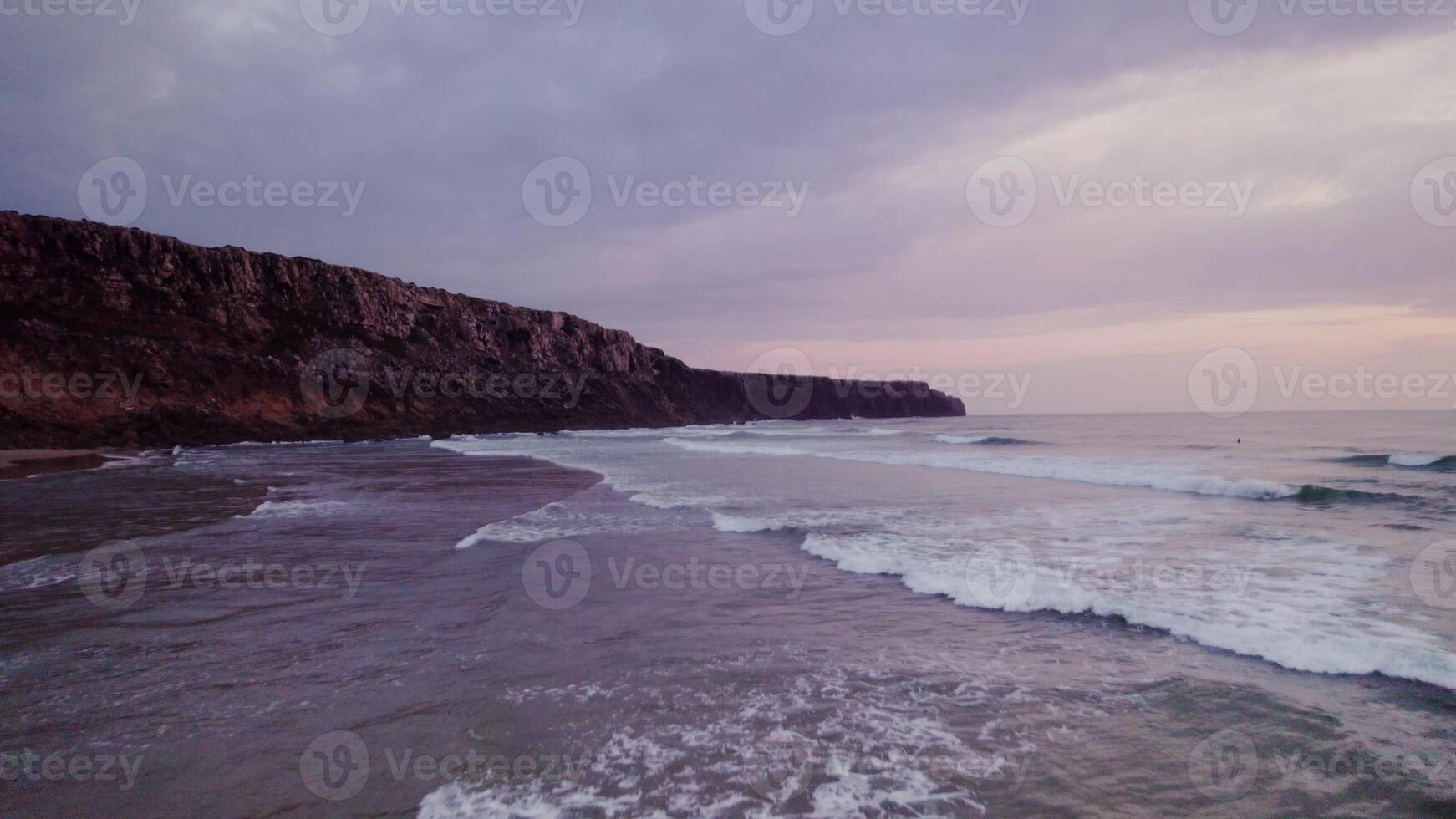 View of the sea near the rocky shore at sunset. Foam waves are beating against the rocks photo