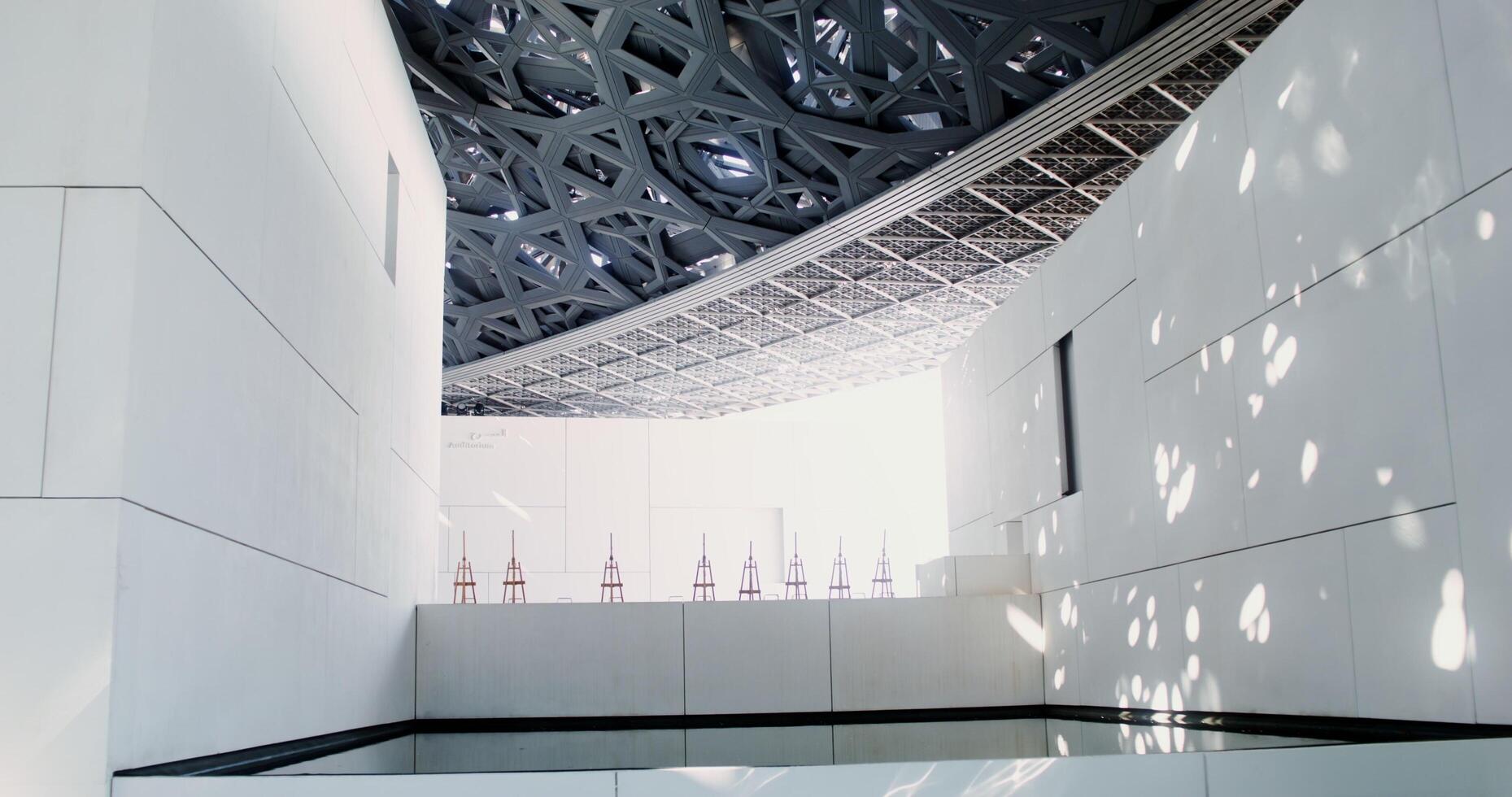 Abu Dhabi, UAE, 2025 - A white minimalistic museum building with empty easels on display. Abstract structure with an openwork ceiling photo