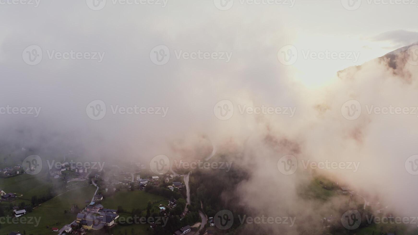 Drone flies high above the clouds hanging over a village at the foot of the Alps. filming in the evening from a bird's eye view. Austria, Alps photo