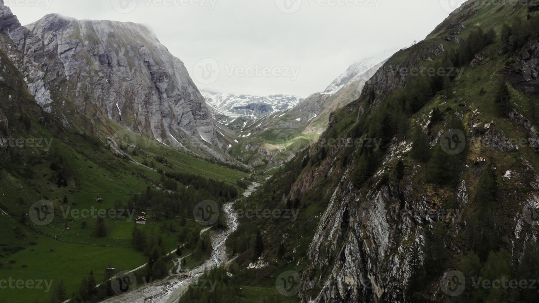 Lonely farm located in lowland between rocky Alpine mountains near a narrow mountain river. Panoramic drone footage, Austria photo