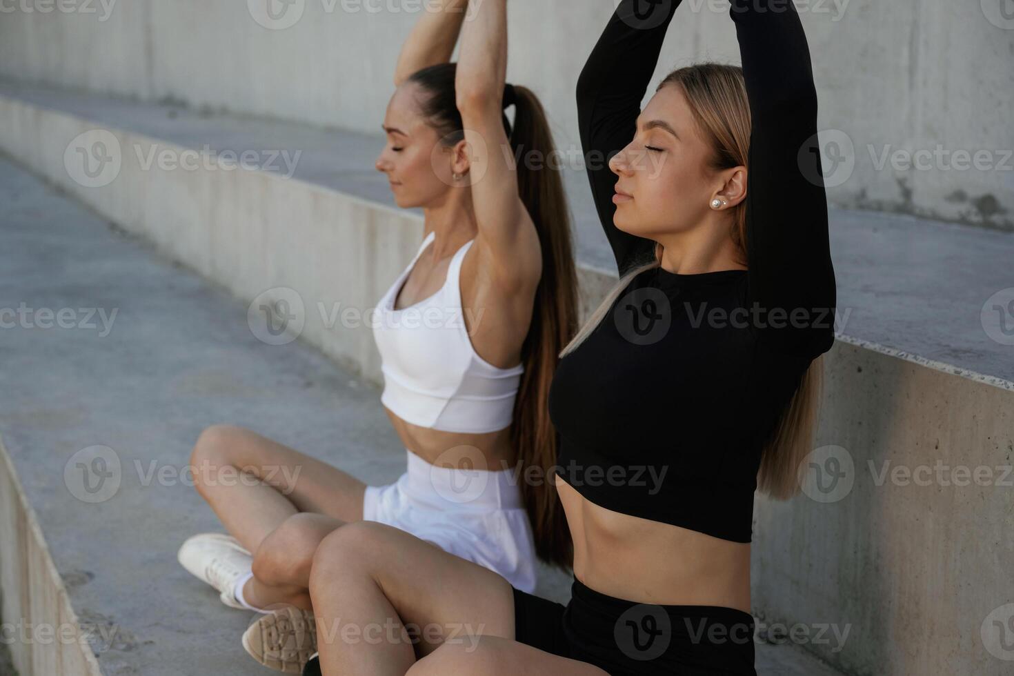 In lotus ,pose, yoga. Two, sportive, women are outdoors together photo
