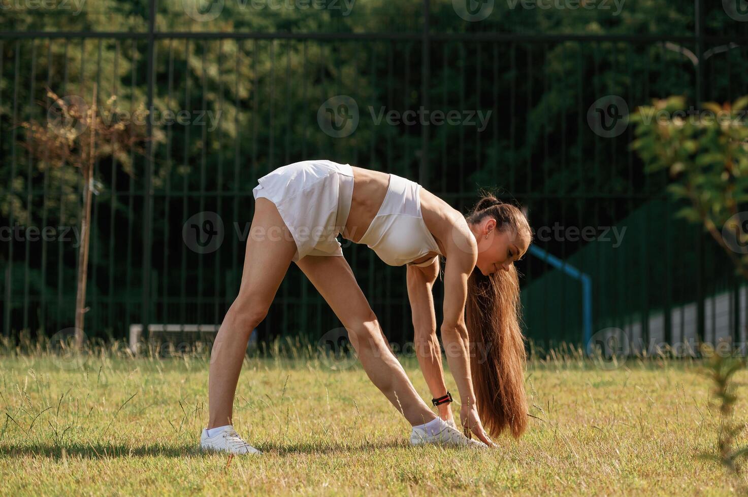 Busy by ,doing exercises. Young skinny fitness woman is outdoors photo