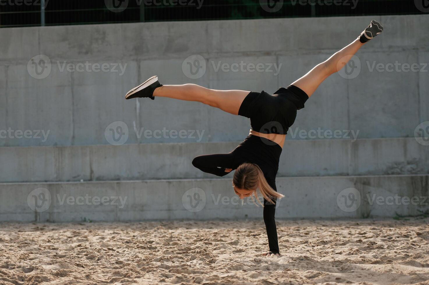Doing tricks.. Beautiful fitness woman in sport clothes is outdoors photo