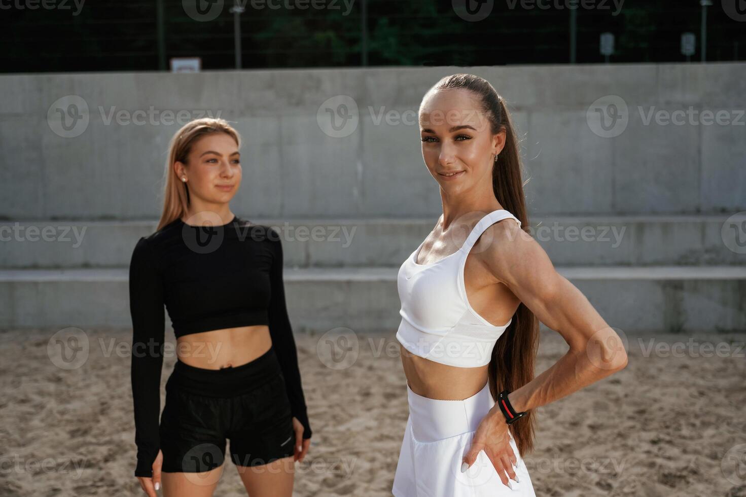 Standing ,and ,,posing. Two sportive women are outdoors together photo