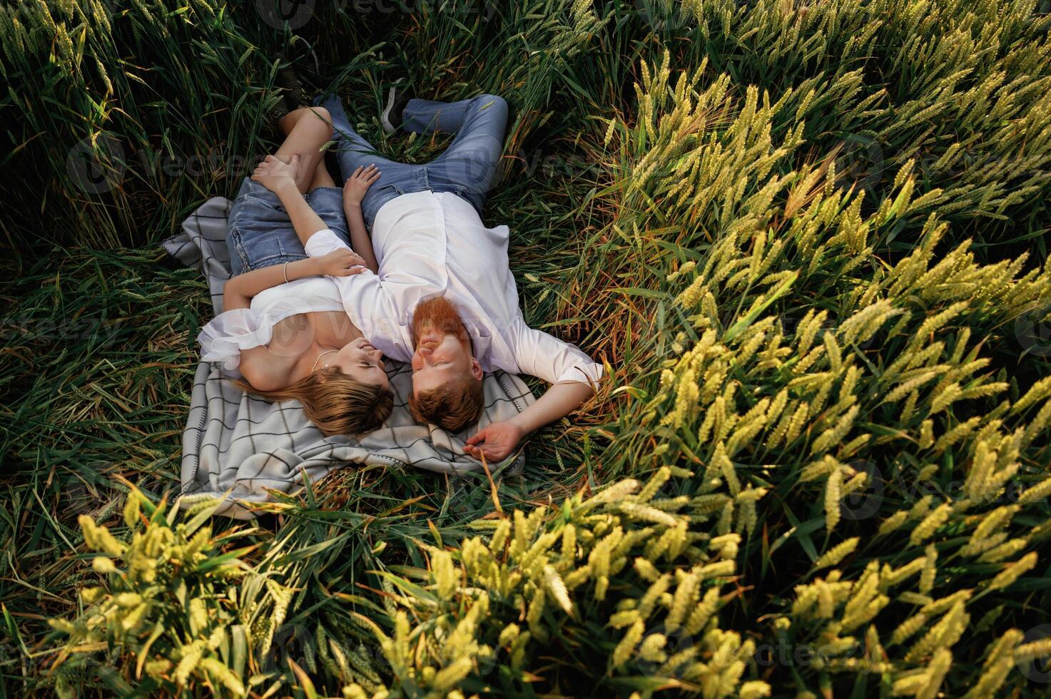 Resting, lying ,down,, top view. Lovely couple are on the green agricultural field together photo