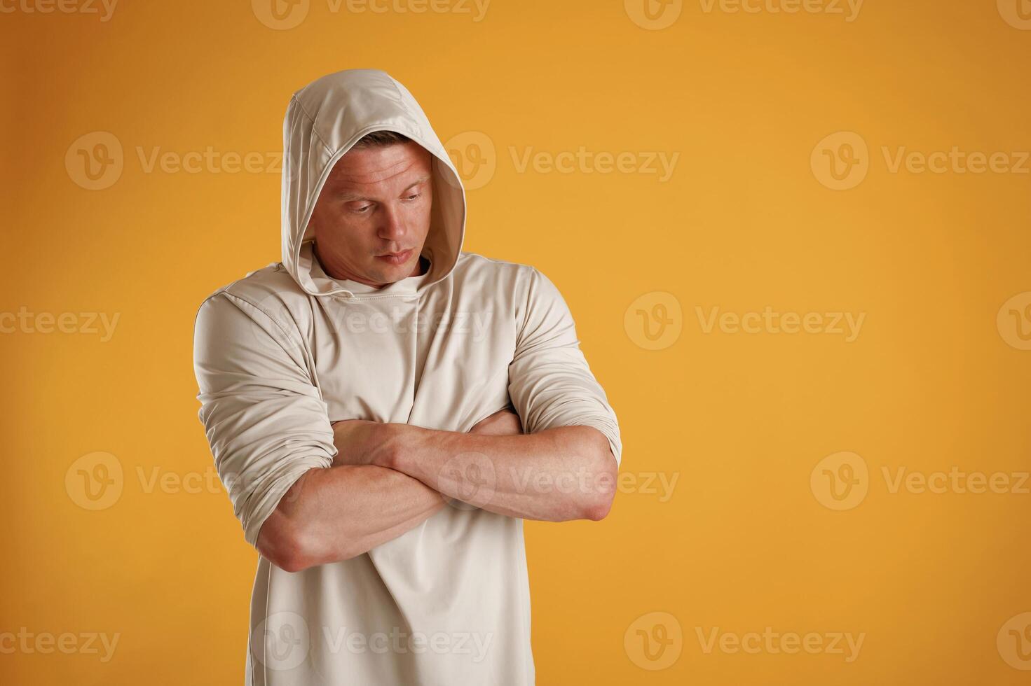 In ,,the ,hoodie, with arms crossed, serious. Man is against background in the studio photo