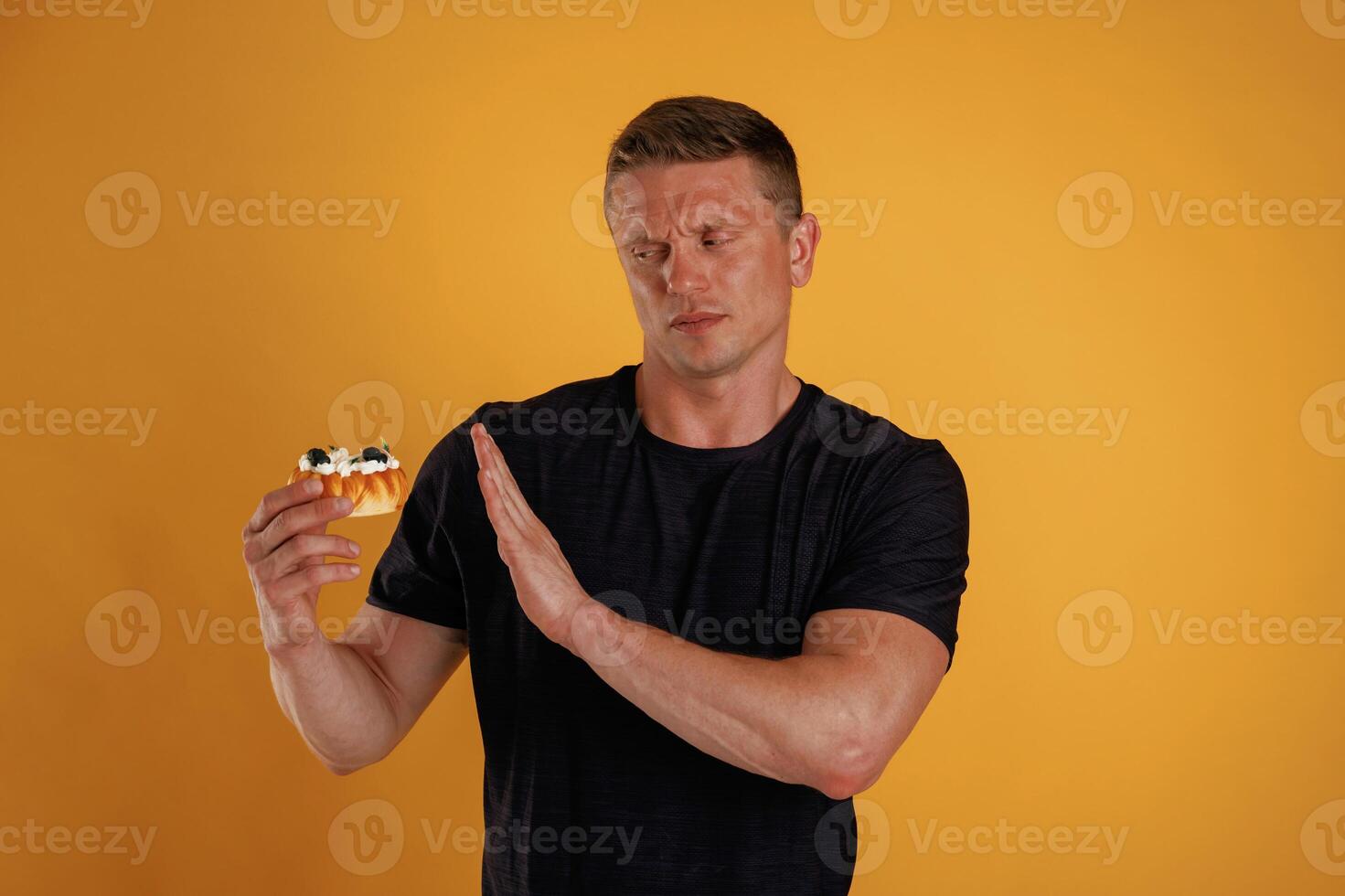 Say, no, to ,sugar, holding cake, don't like it. Man is against background in the studio photo