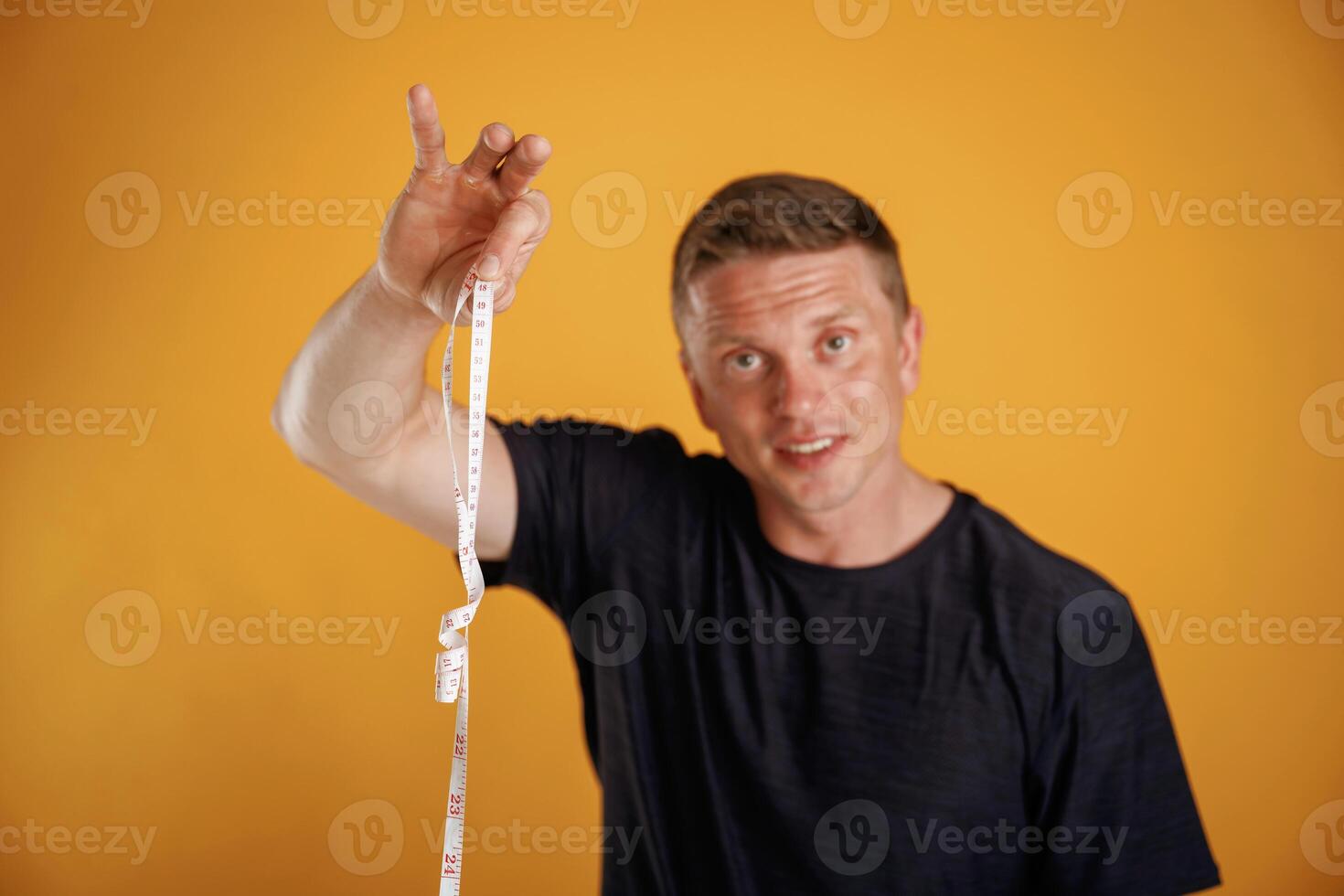 Measuring tape in hand, fitness conception... Man is against background in the studio photo