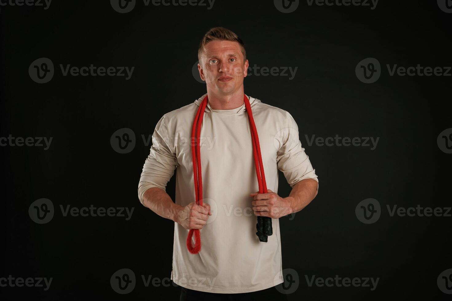 Red jump ropes, endurance and, sport concept. Man is against background in the studio photo