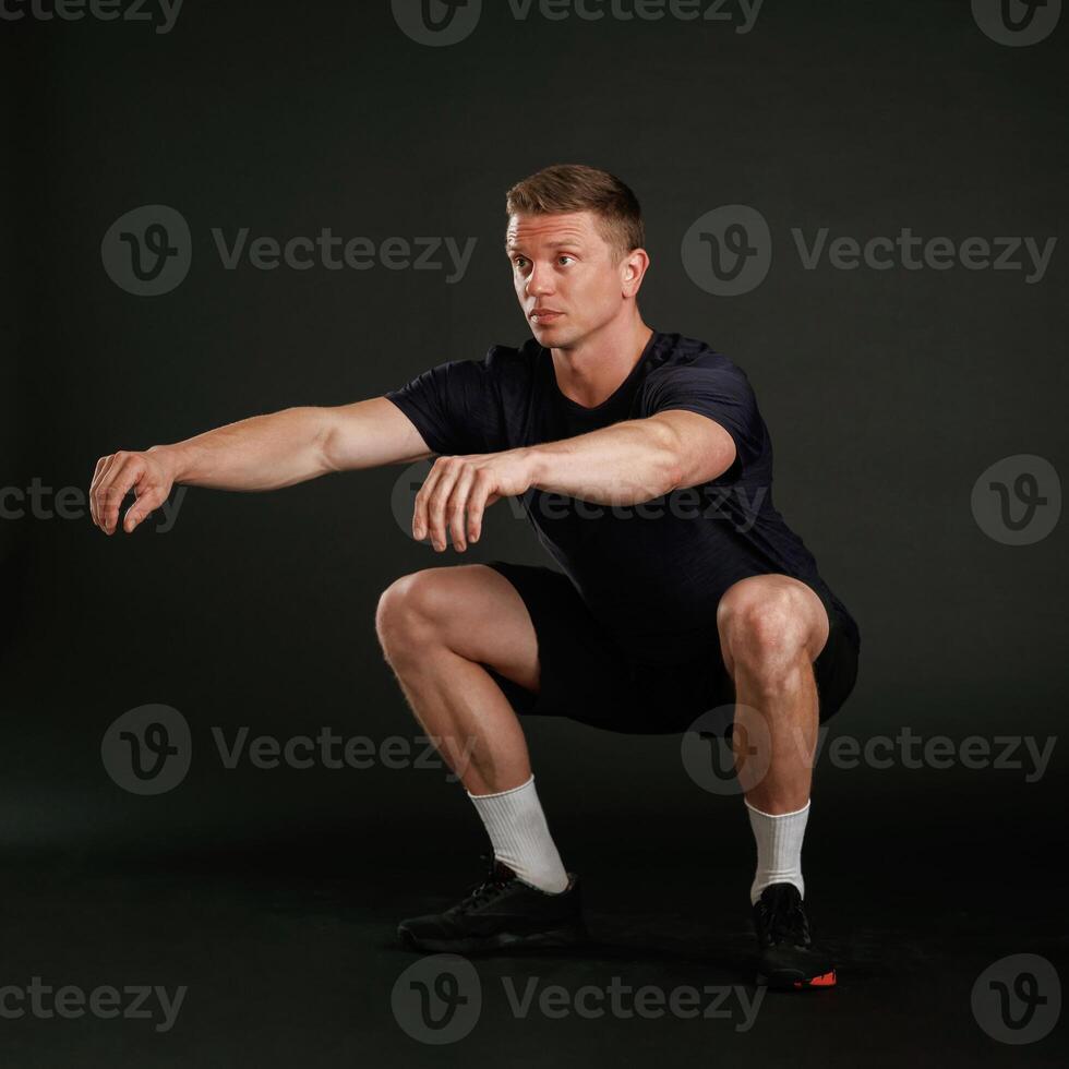 Squats exercise. Man is against background in the studio photo
