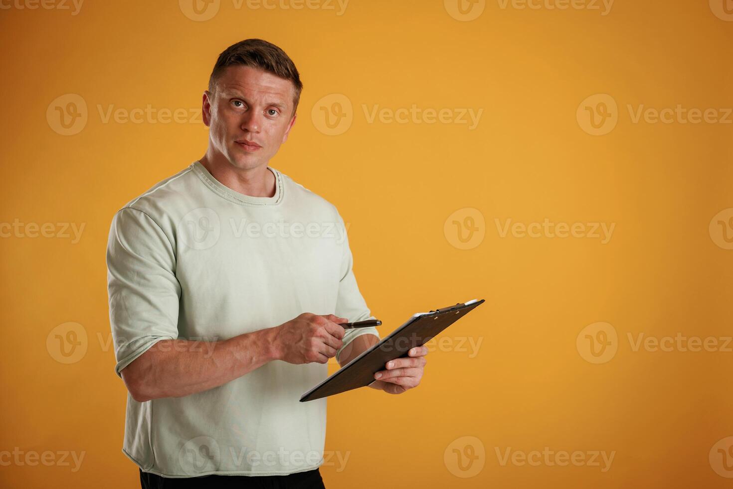 With notepad and pen.. Man is against background in the studio photo