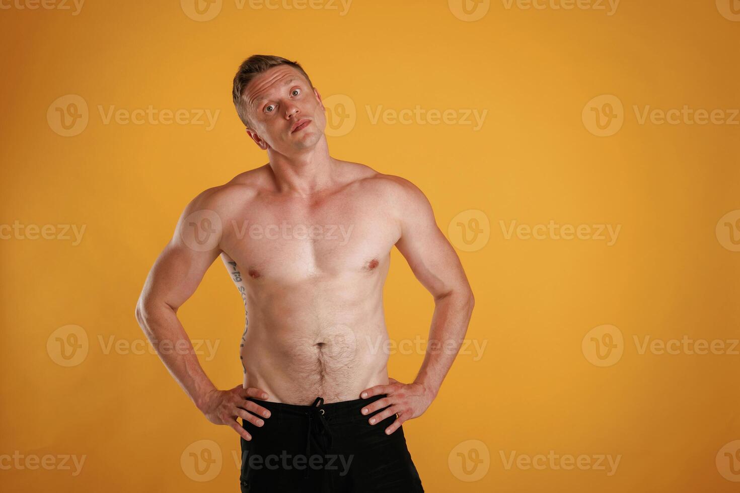 Shirtless, standing.. Man is against background in the studio photo
