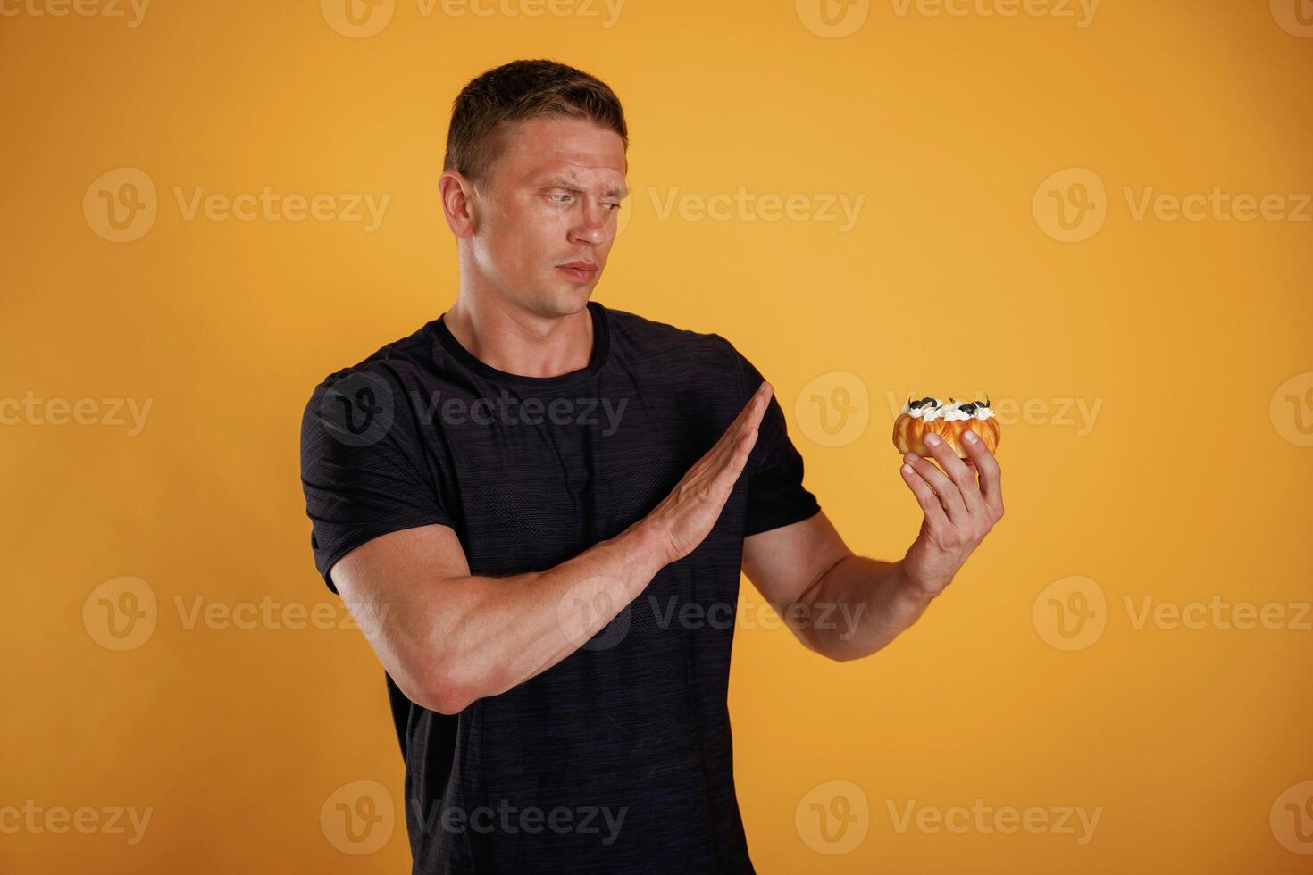 Say no ,to, sugar, holding cake, don't like it. Man is against background in the studio photo
