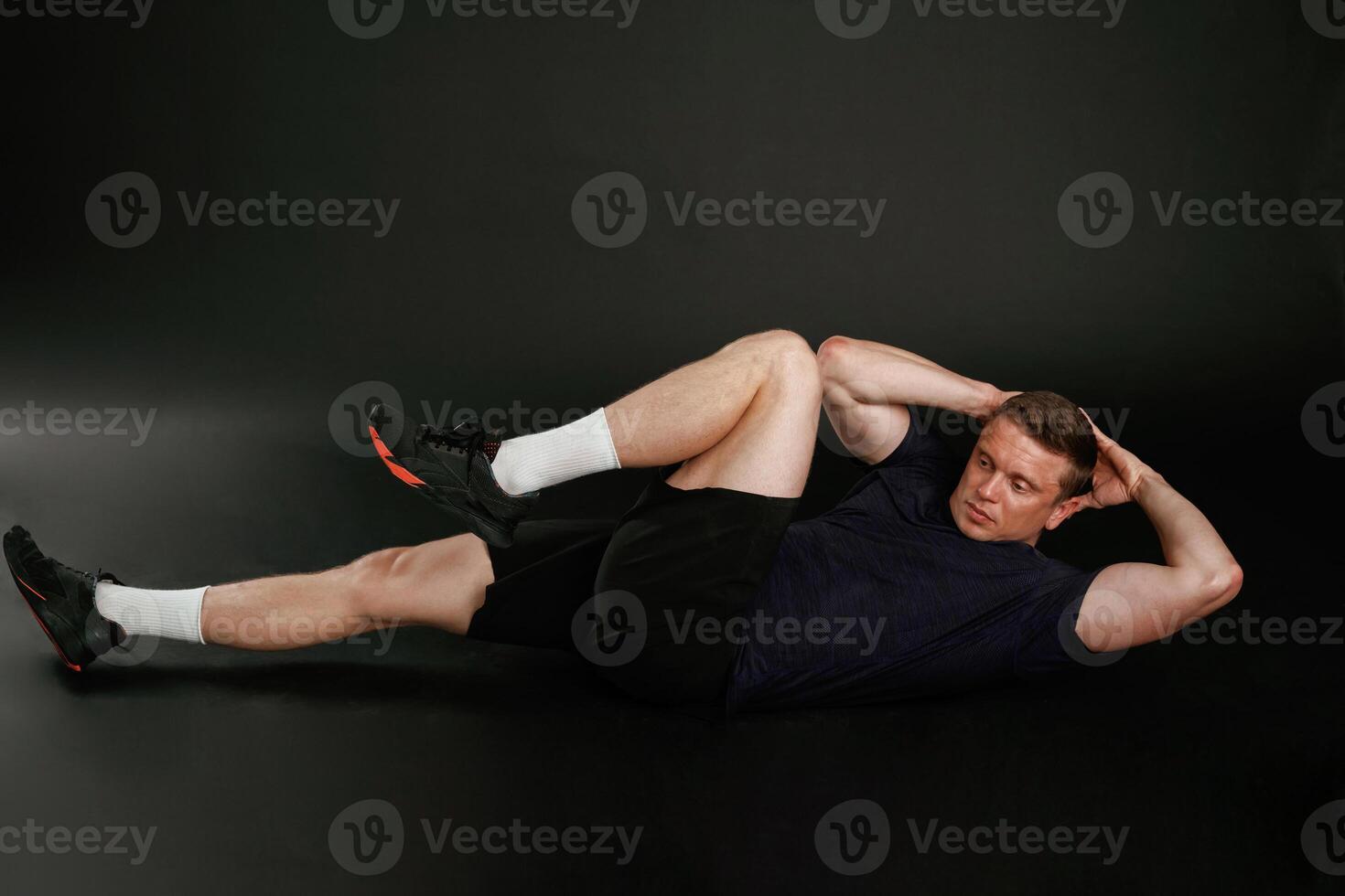 Abs exercise. Man is against background in the studio photo