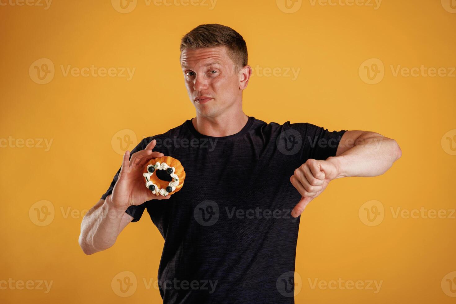 Say ,,no to sugar, holding cake, don't like it. Man is against background in the studio photo