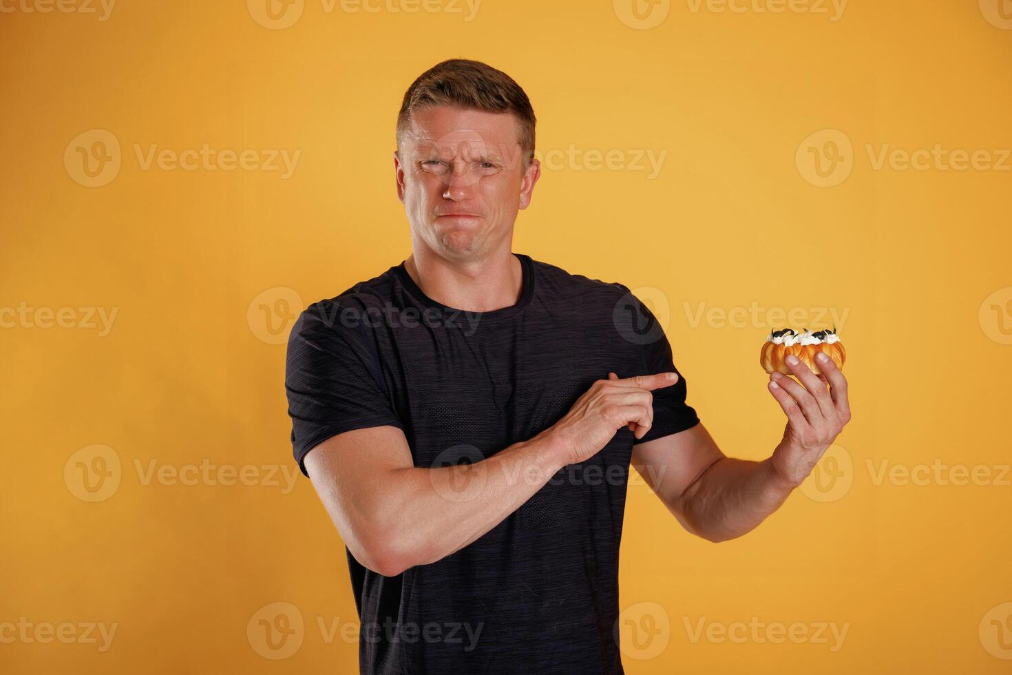Say, no to sugar, holding cake, don't like it. Man is against background in the studio photo