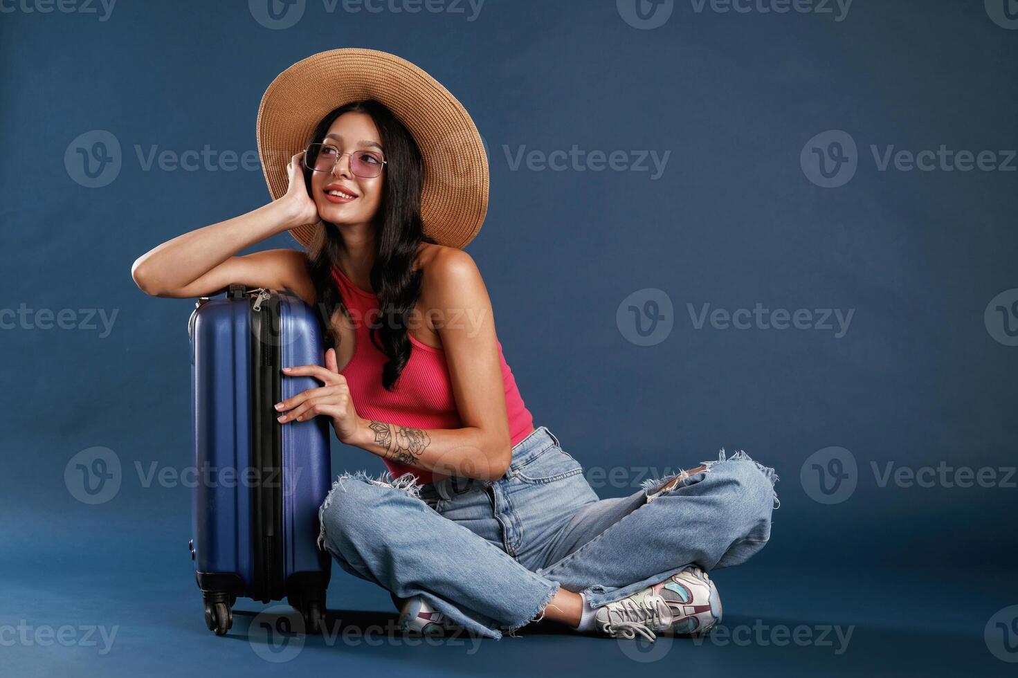 Taking a rest, sitting ,with suitcase. Beautiful young woman is against background photo