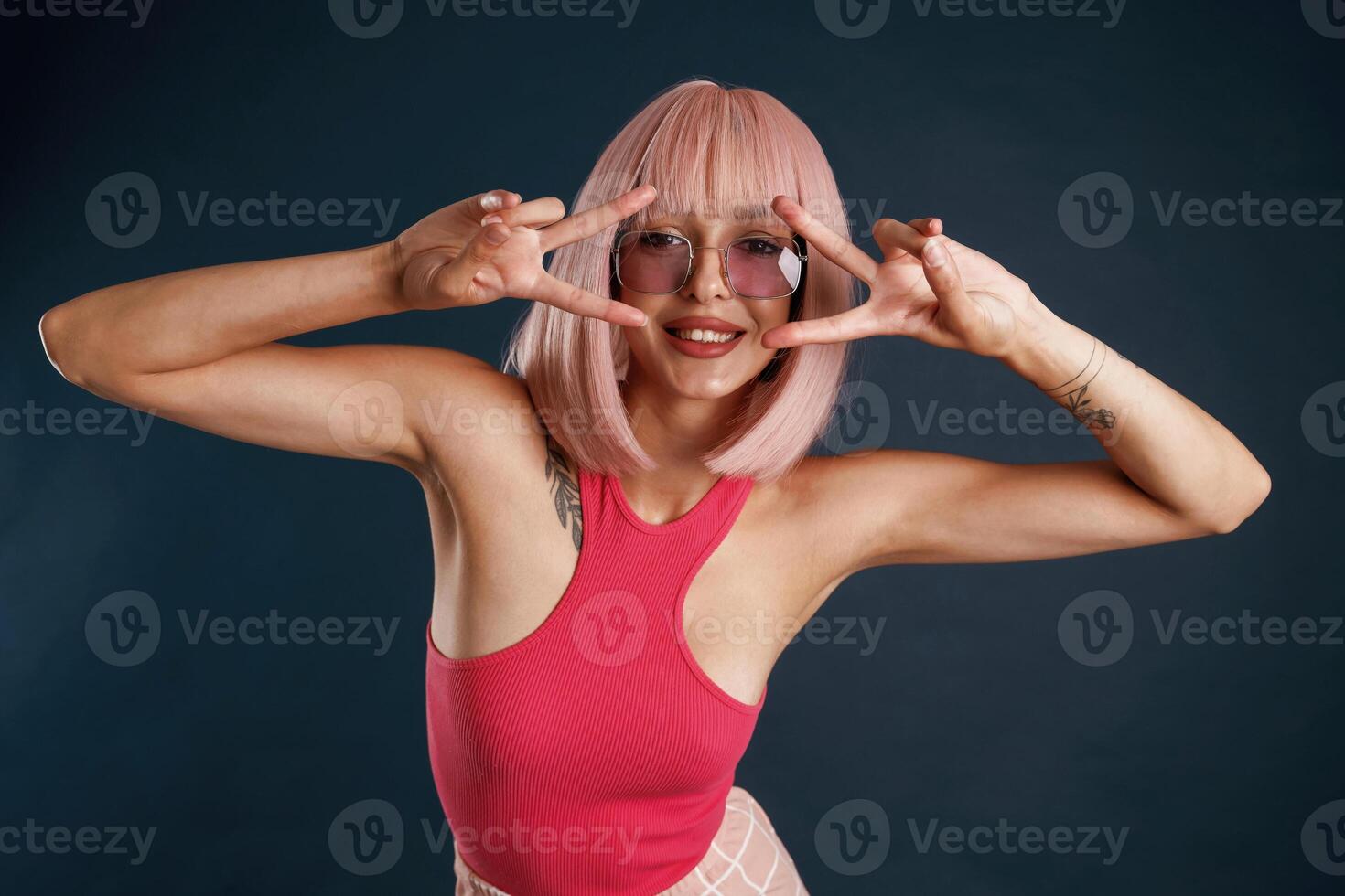 Happy, hands and fingers gesture, cute pink hair. Beautiful young woman is against background photo