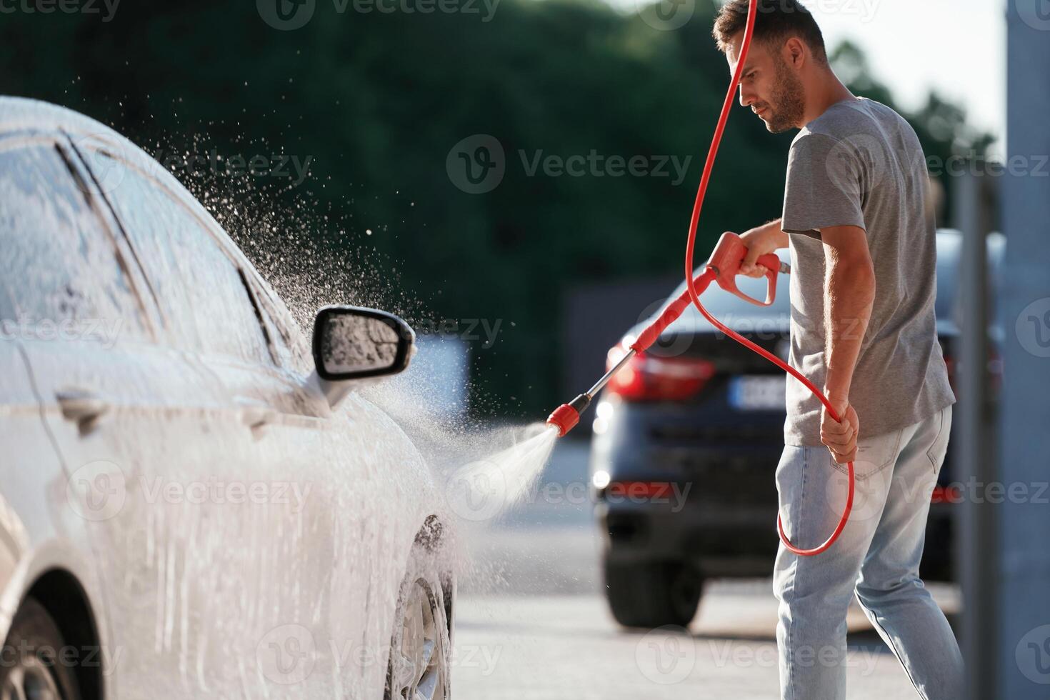 Water high pressure stream, car wash. Man is with his automobile outdoors photo