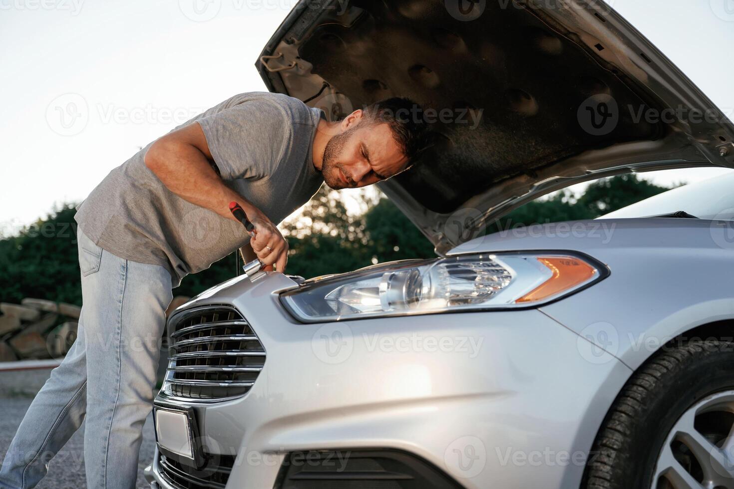 Hood ,,,is, opened, repairing.,, Man is with his car outdoors photo