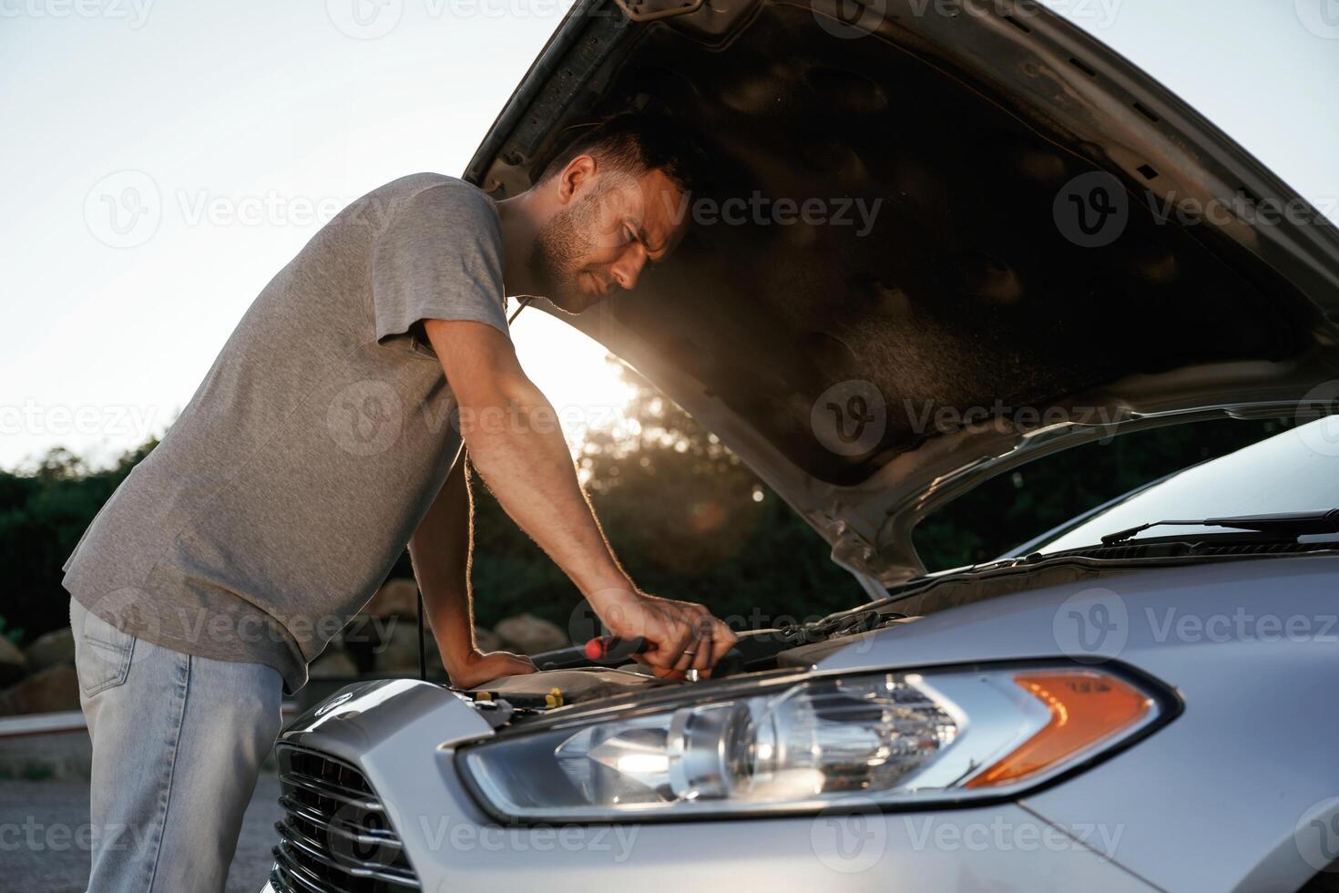 Hood ,is opened, repairing. Man ,,is with, his car outdoors photo