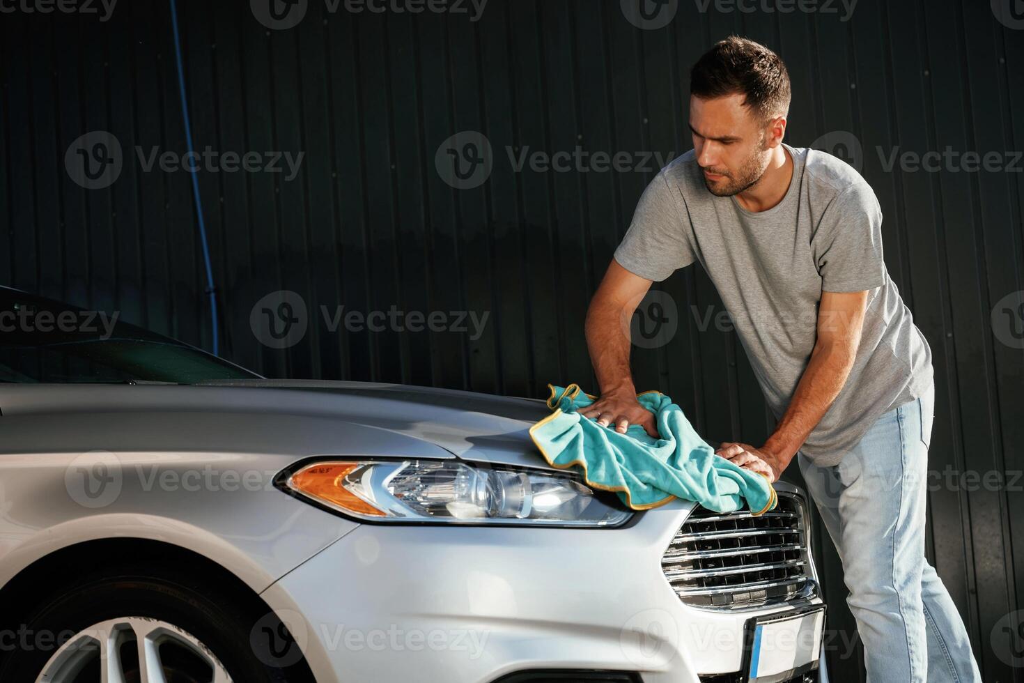 View from the side, using ,cloth,, to, polish the automobile. Man is with his car outdoors photo