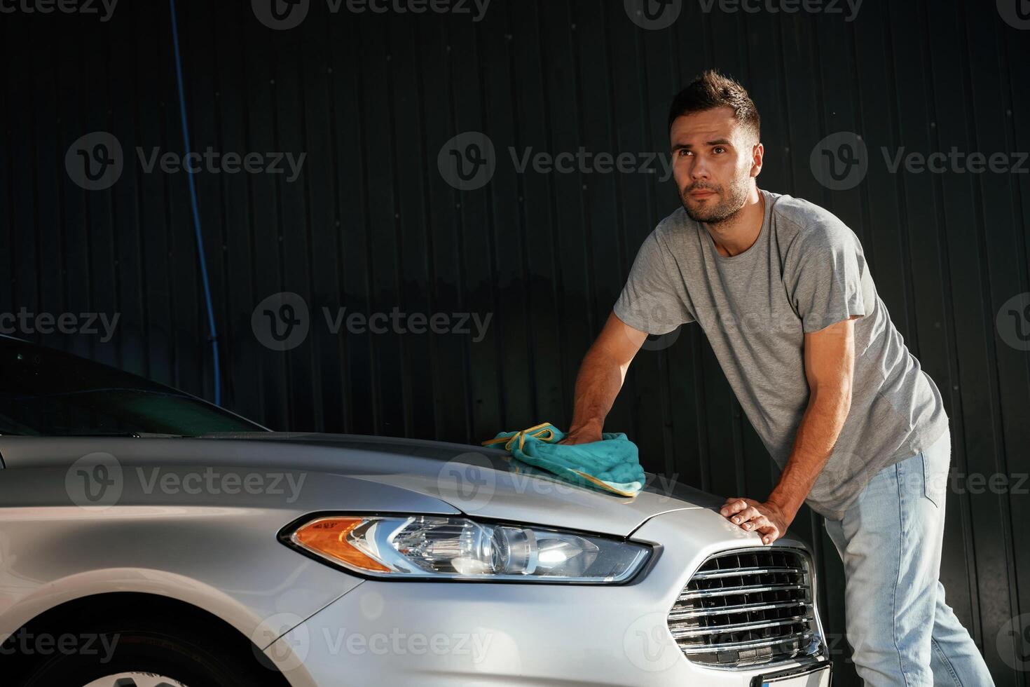 View from the side, using ,cloth, to ,polish the automobile. Man is with his car outdoors photo