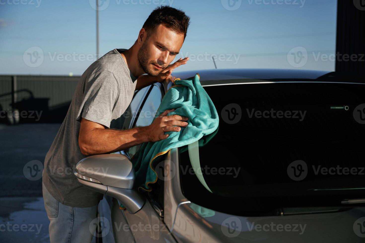 Turquoise cloth, polishing the vehicle.... Man is with his car outdoors photo