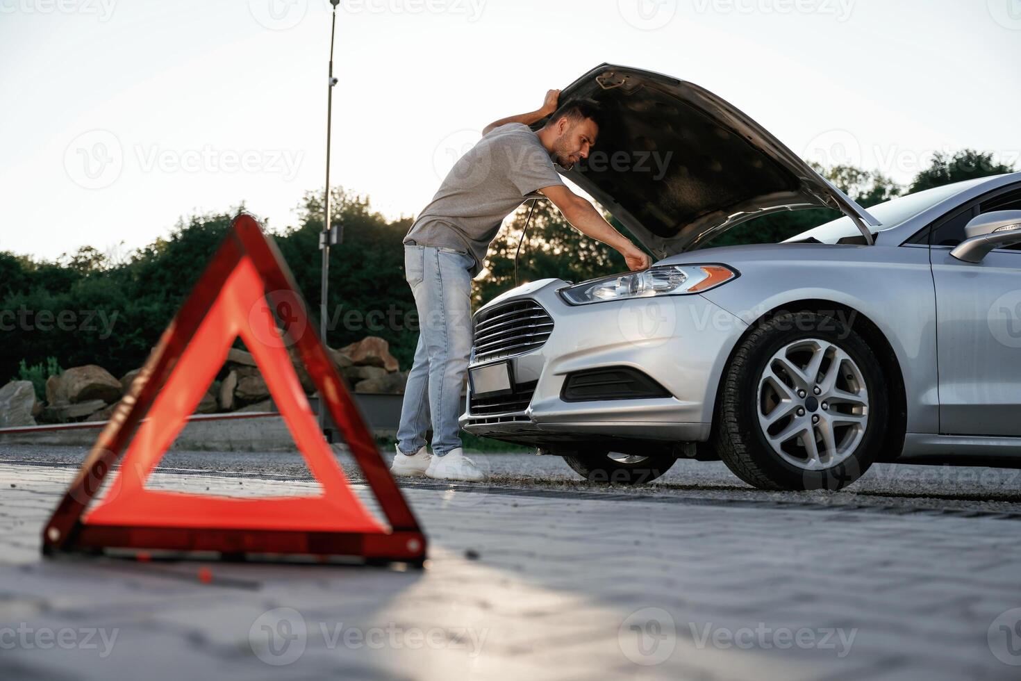 Under the sunlight, red sign, accident, broken automobile, repair. Man is with his car outdoors photo