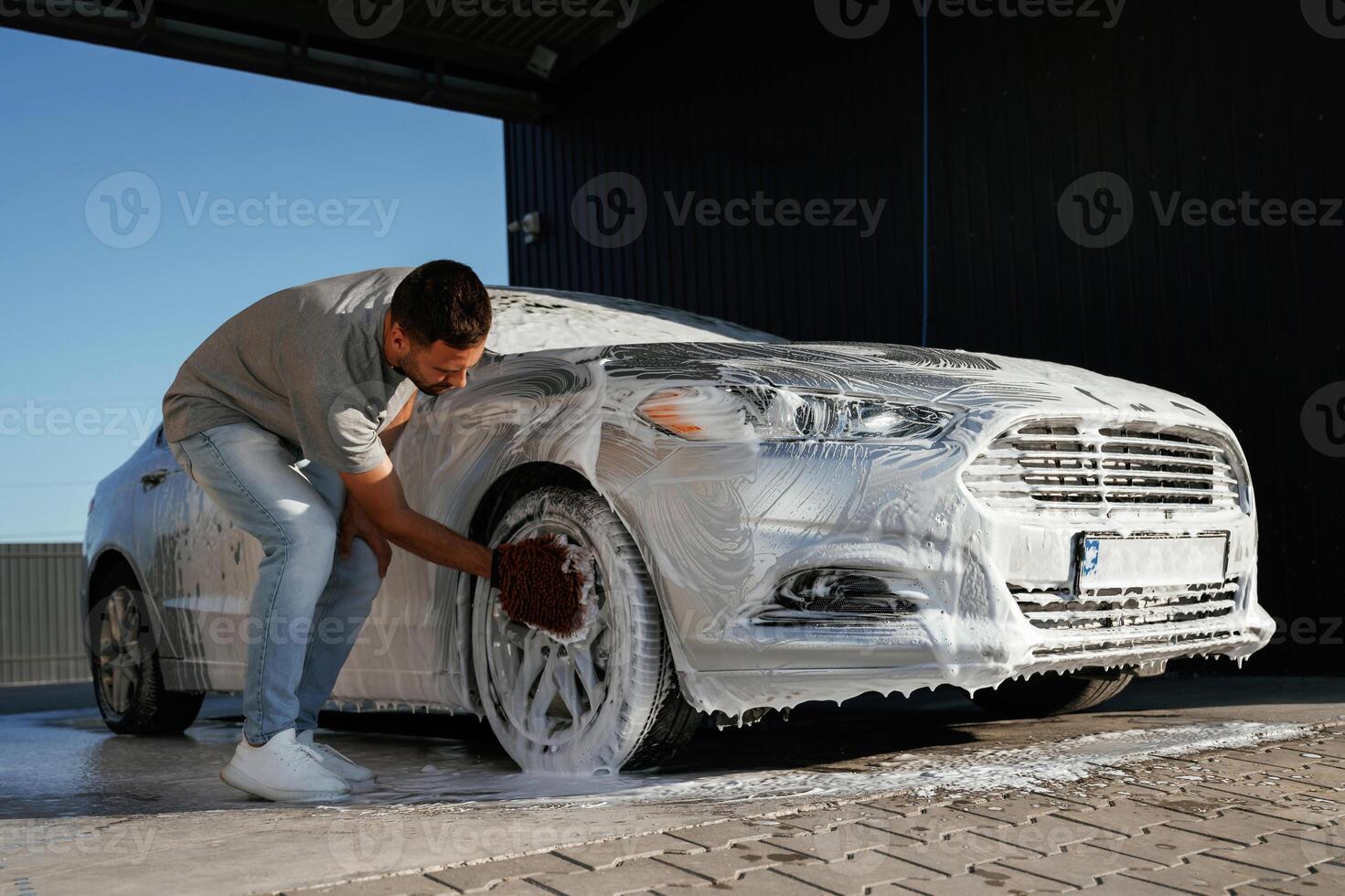 White soap and foam, ,,washing ,the ,automobile. Man is with his car outdoors photo