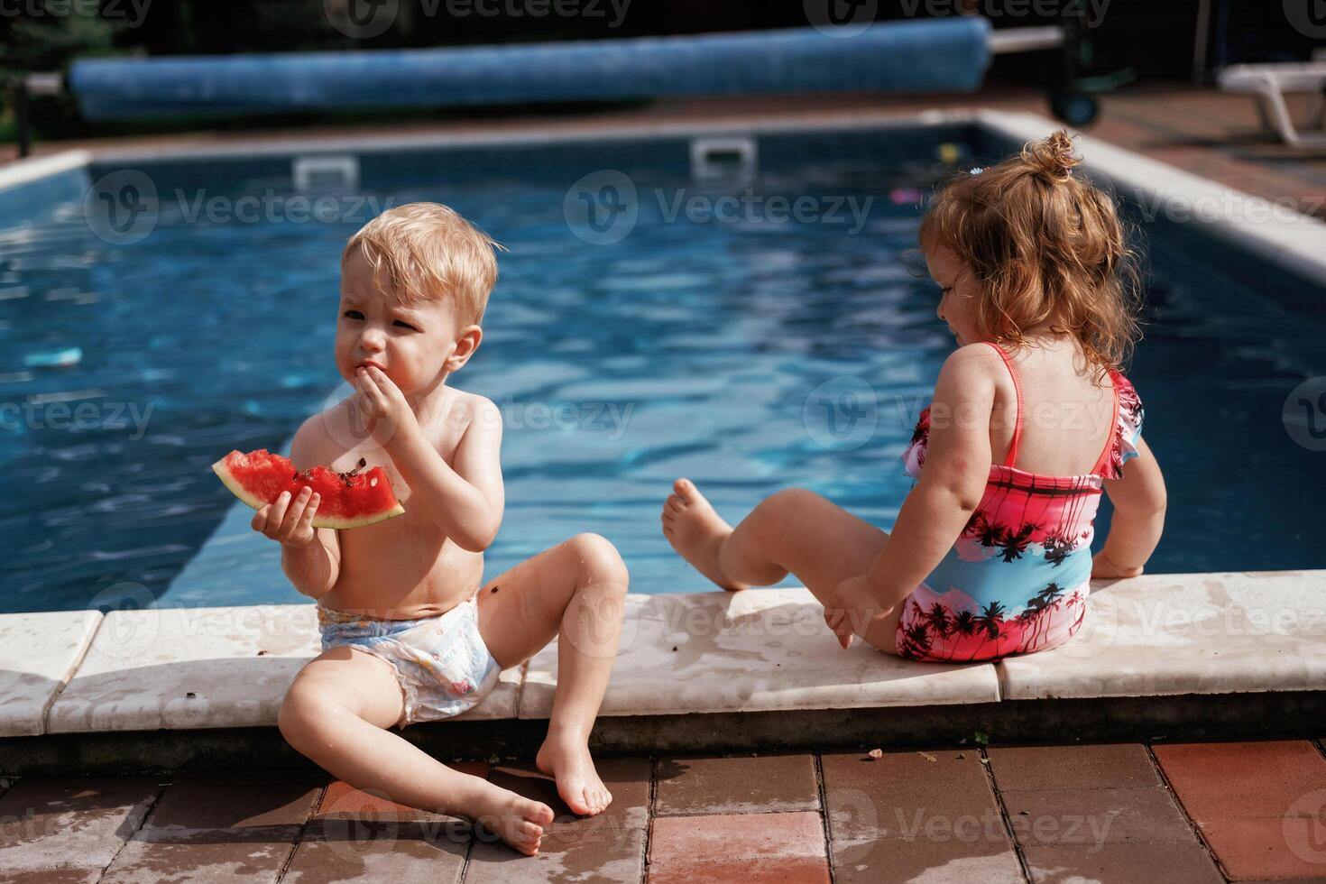 Eating tasty watermelon. Boy, and ,girl are having fun by the pool photo