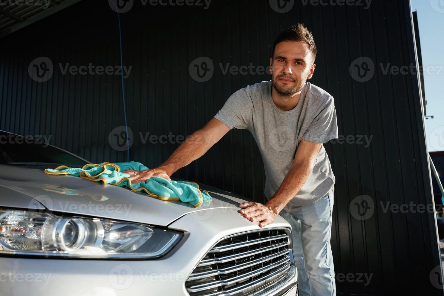 With, cloth, in hands. Car wash. Man is with automobile outdoors photo