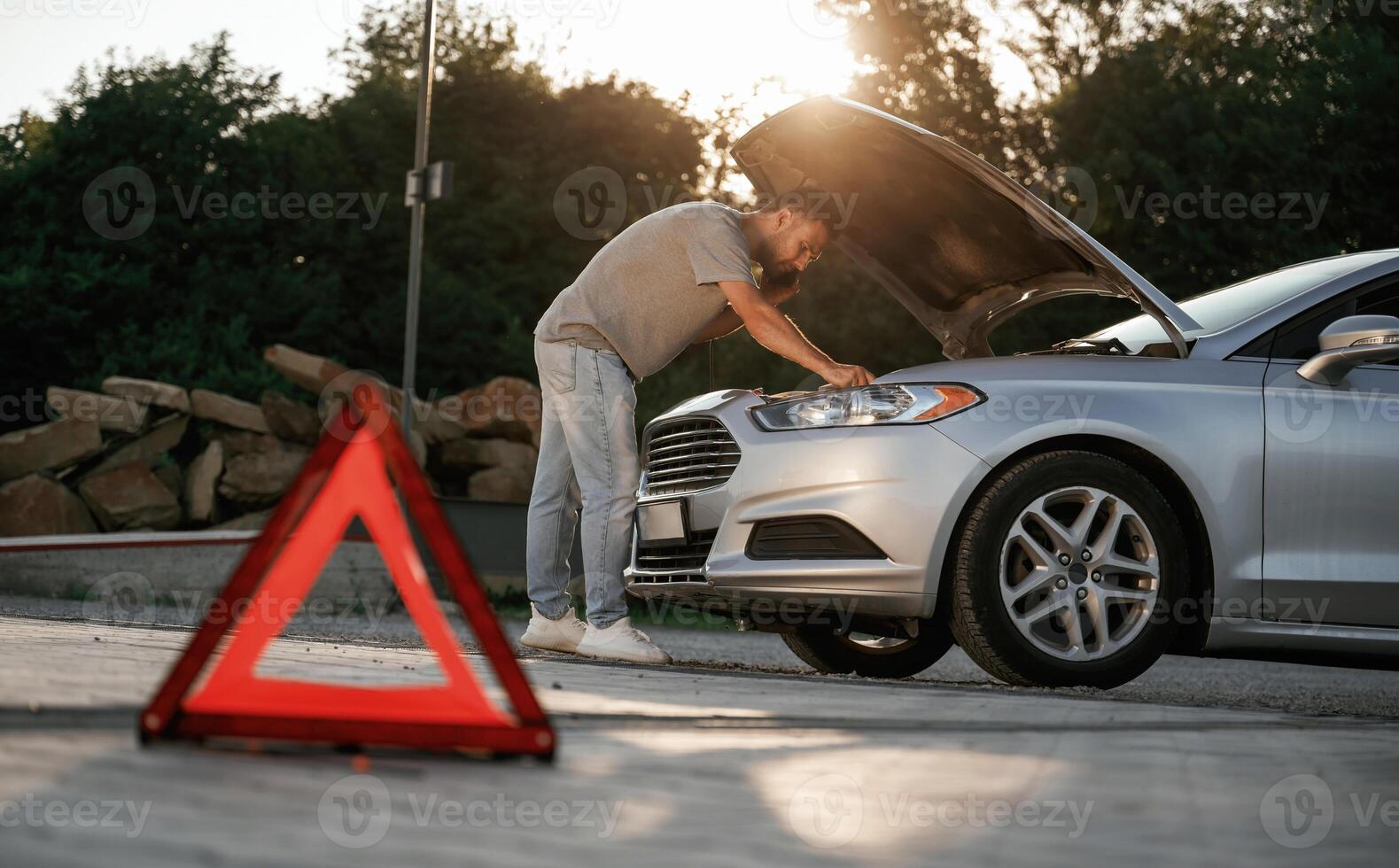 Under the ,sunlight, red sign, accident, broken automobile, repair. Man is with his car outdoors photo