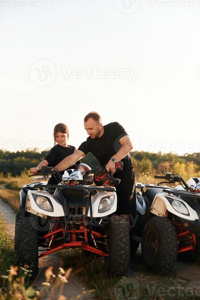 Showing how, the machine works., Father and daughter are with ATV outdoors photo