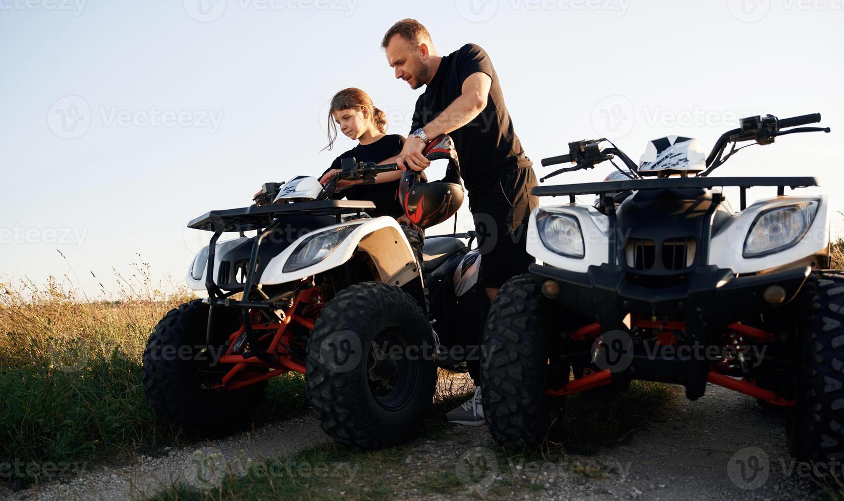 Showing, how, the machine works. Father and daughter are with ATV outdoors photo