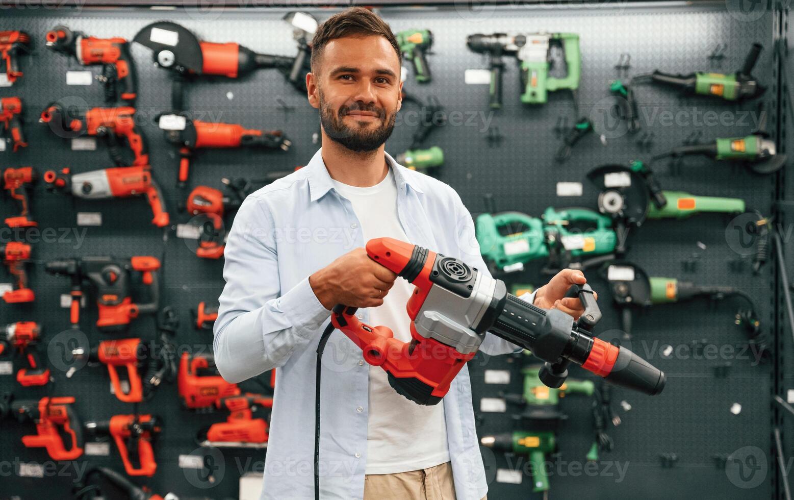 Plural,, perforator in hands. Man is in the, hardware shop photo