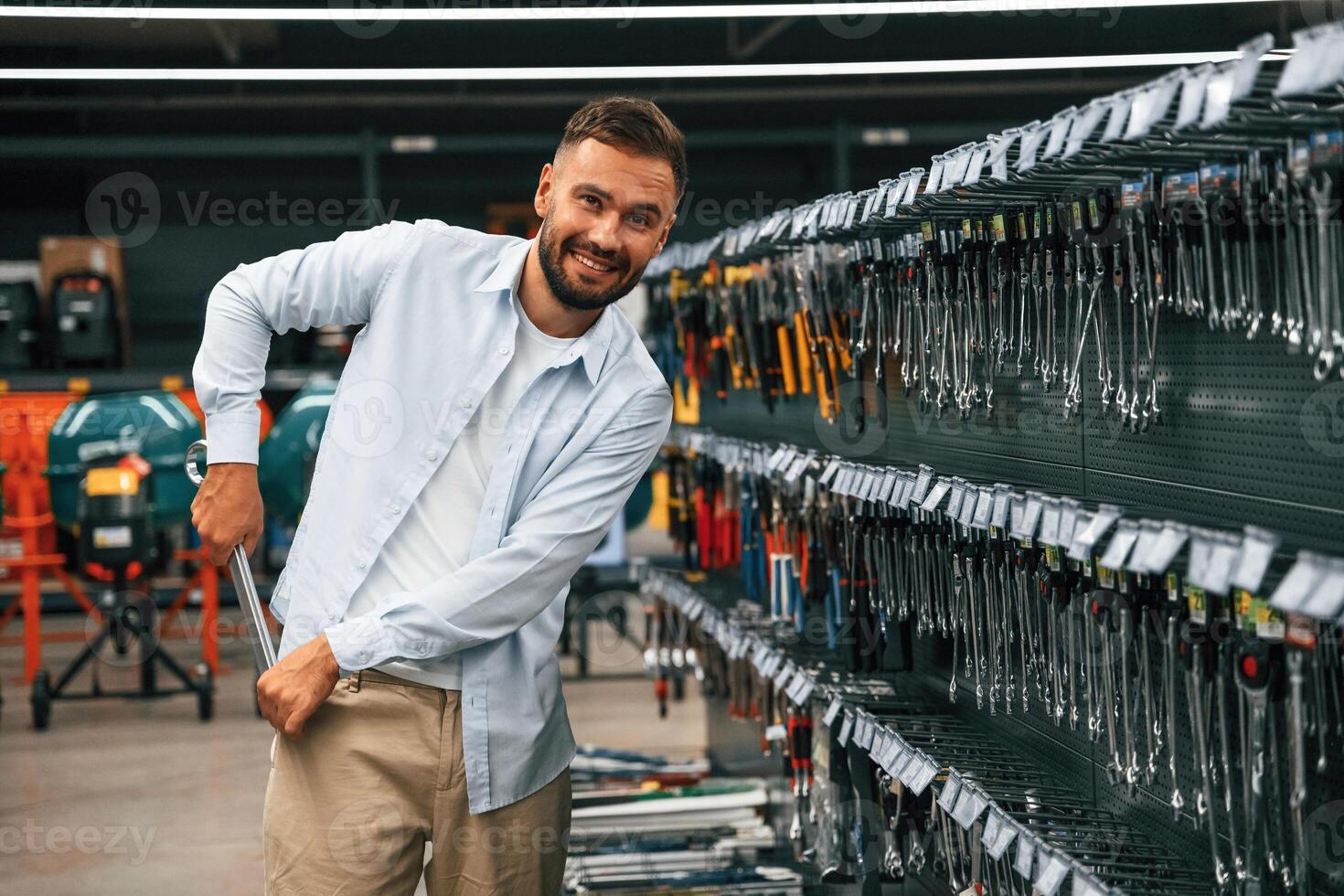 Stealing the wrench, smiling. Man is in the hardware shop photo